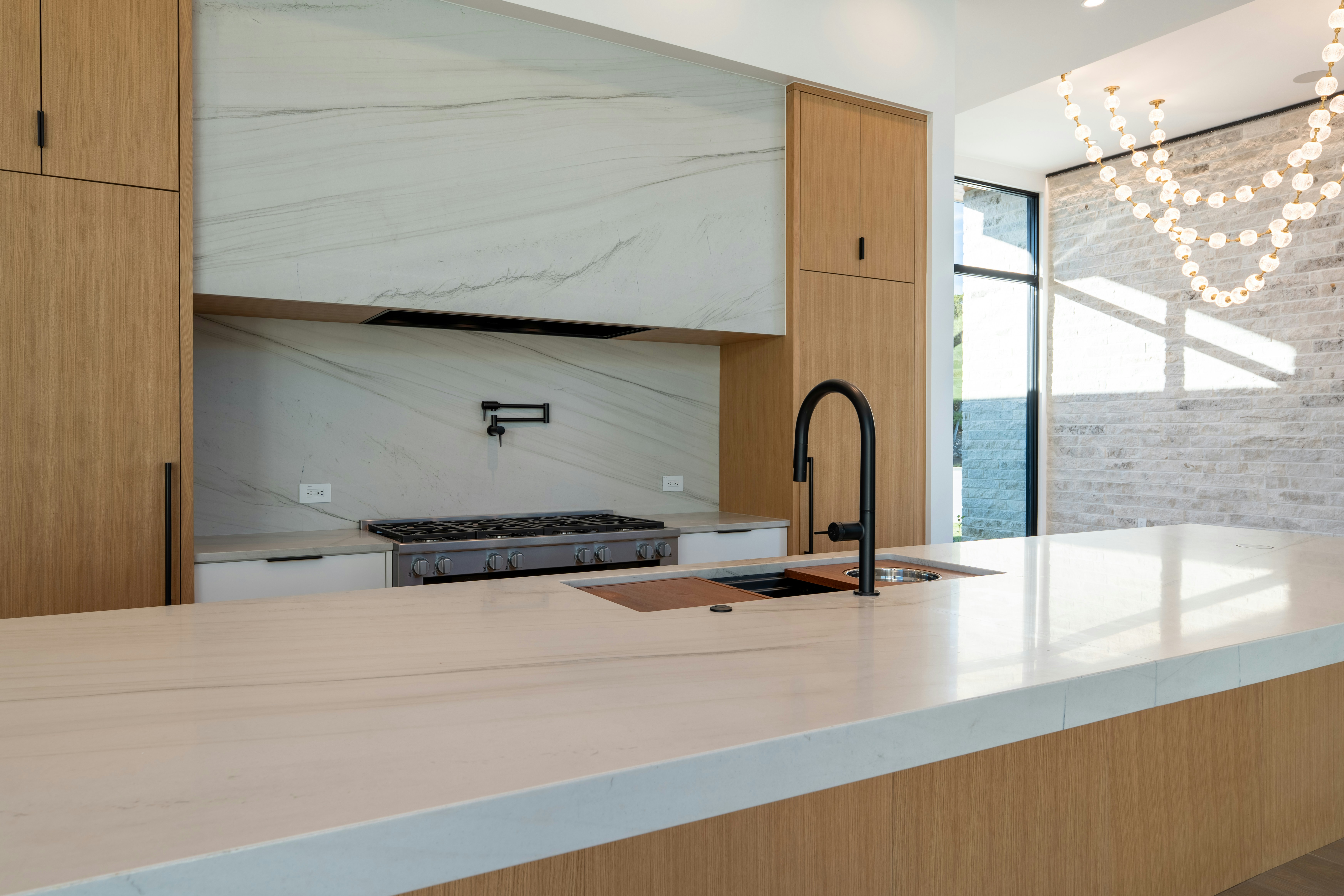 Sleek modern kitchen with wood cabinets and marble countertops.