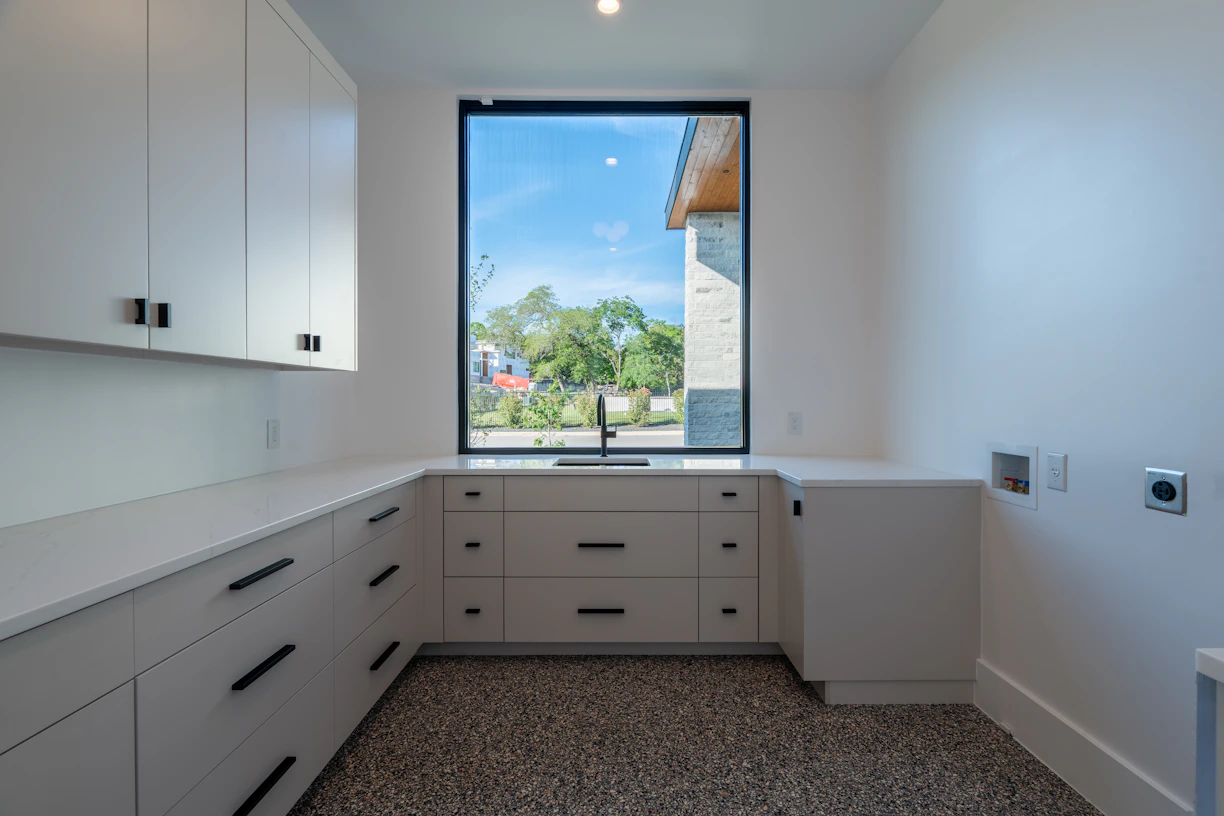 Modern white laundry room with large window and sink