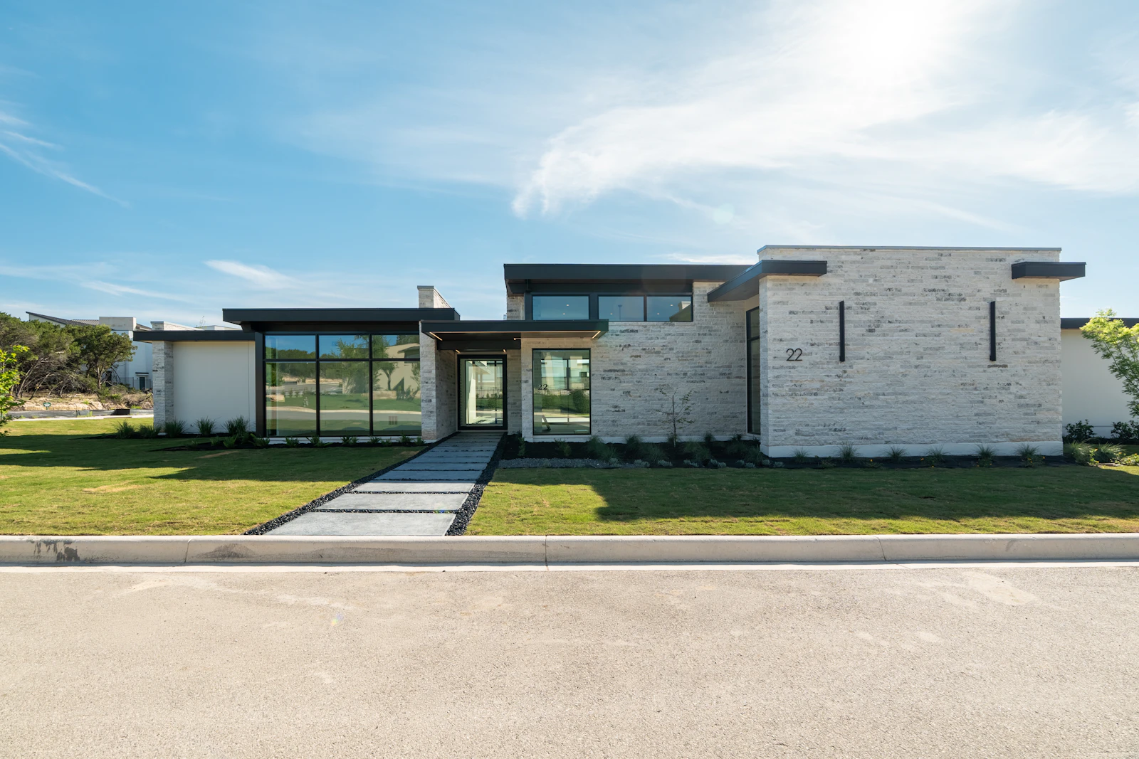 Modern stone home with a wide lawn and clean-lined entry