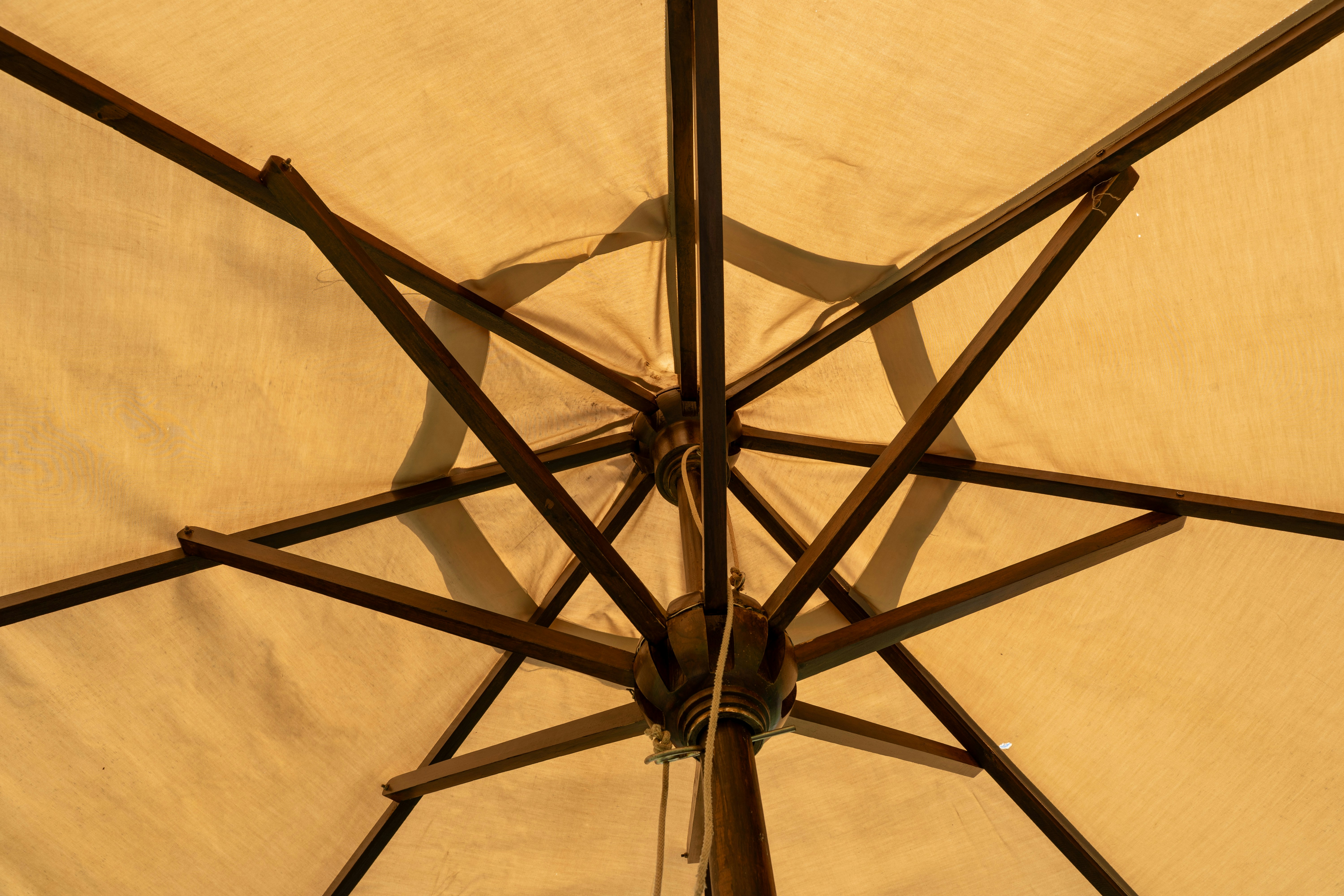 La structure en bois du parasol beige vue en dessous.