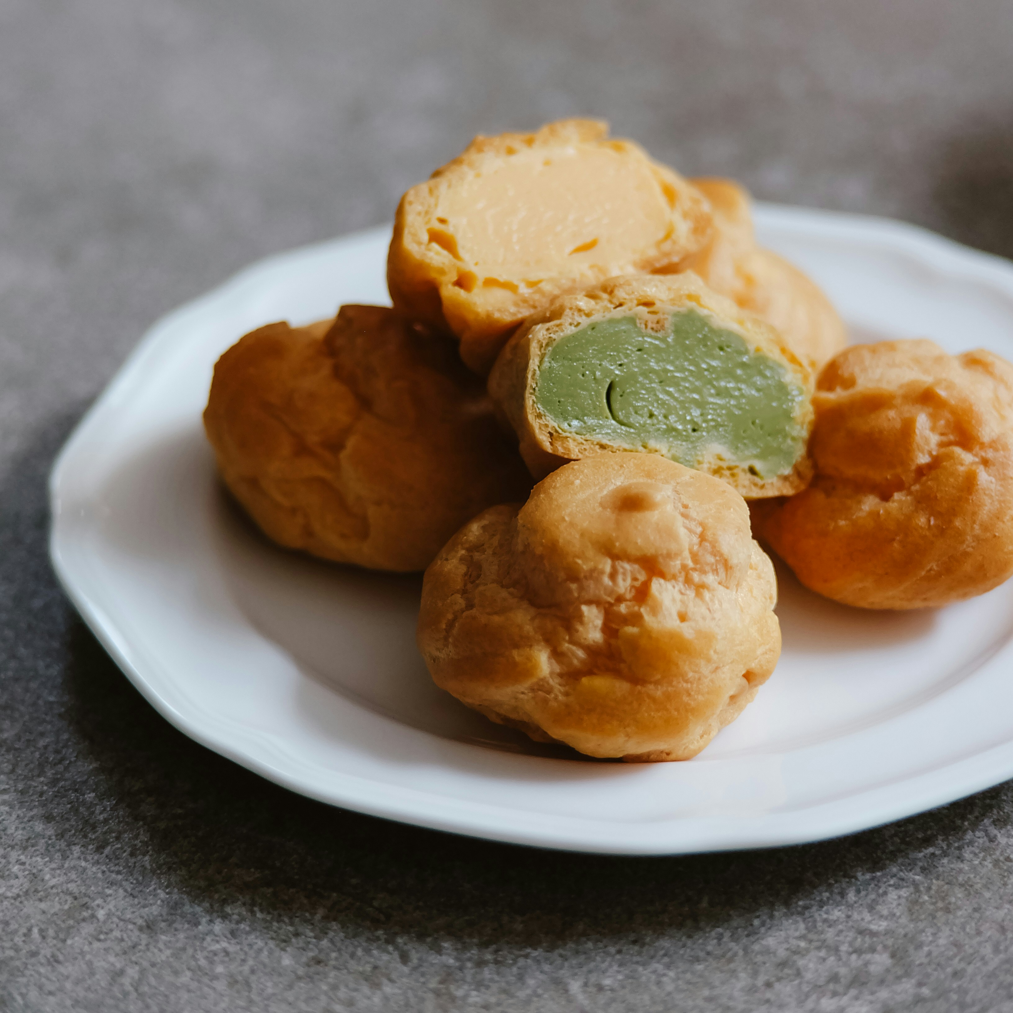 Golden cream puffs with green and yellow fillings.