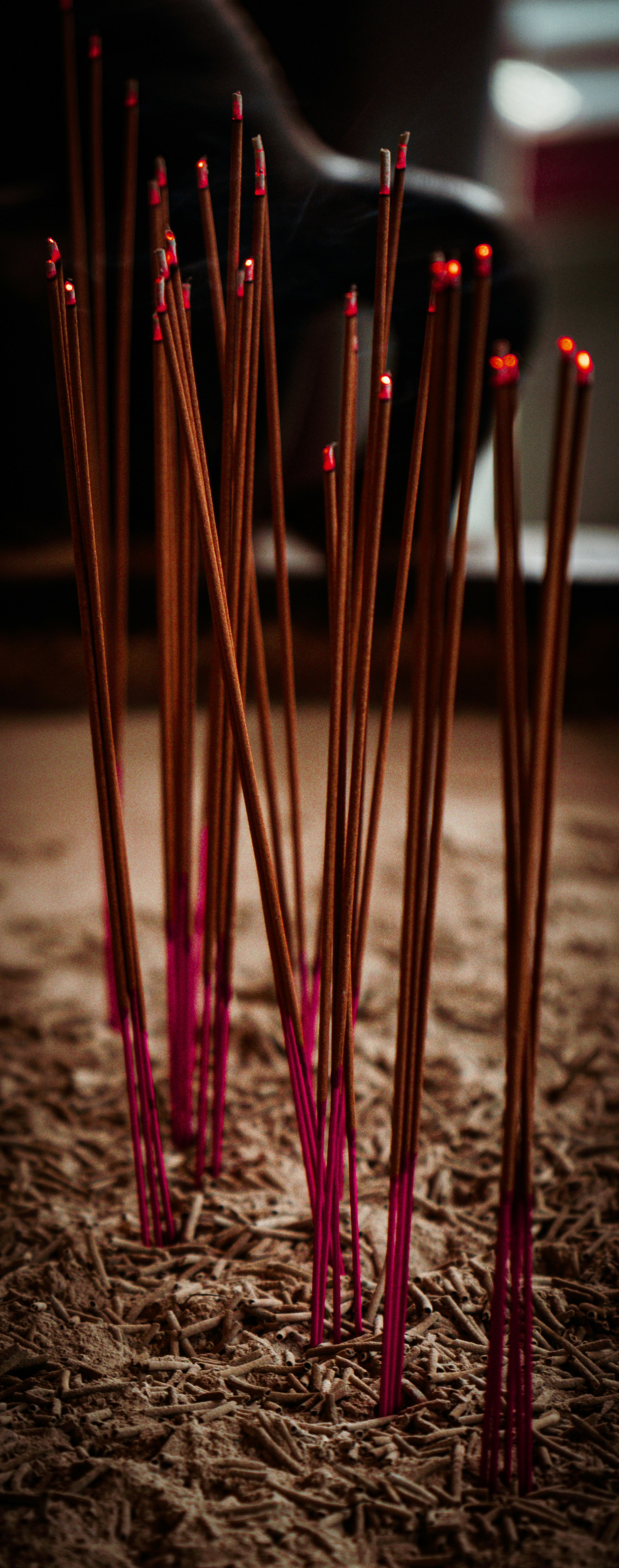 Burning incense sticks glowing red in an ash bed