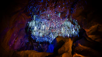 Glowing blue and purple icicle-like formations in a dark cave
