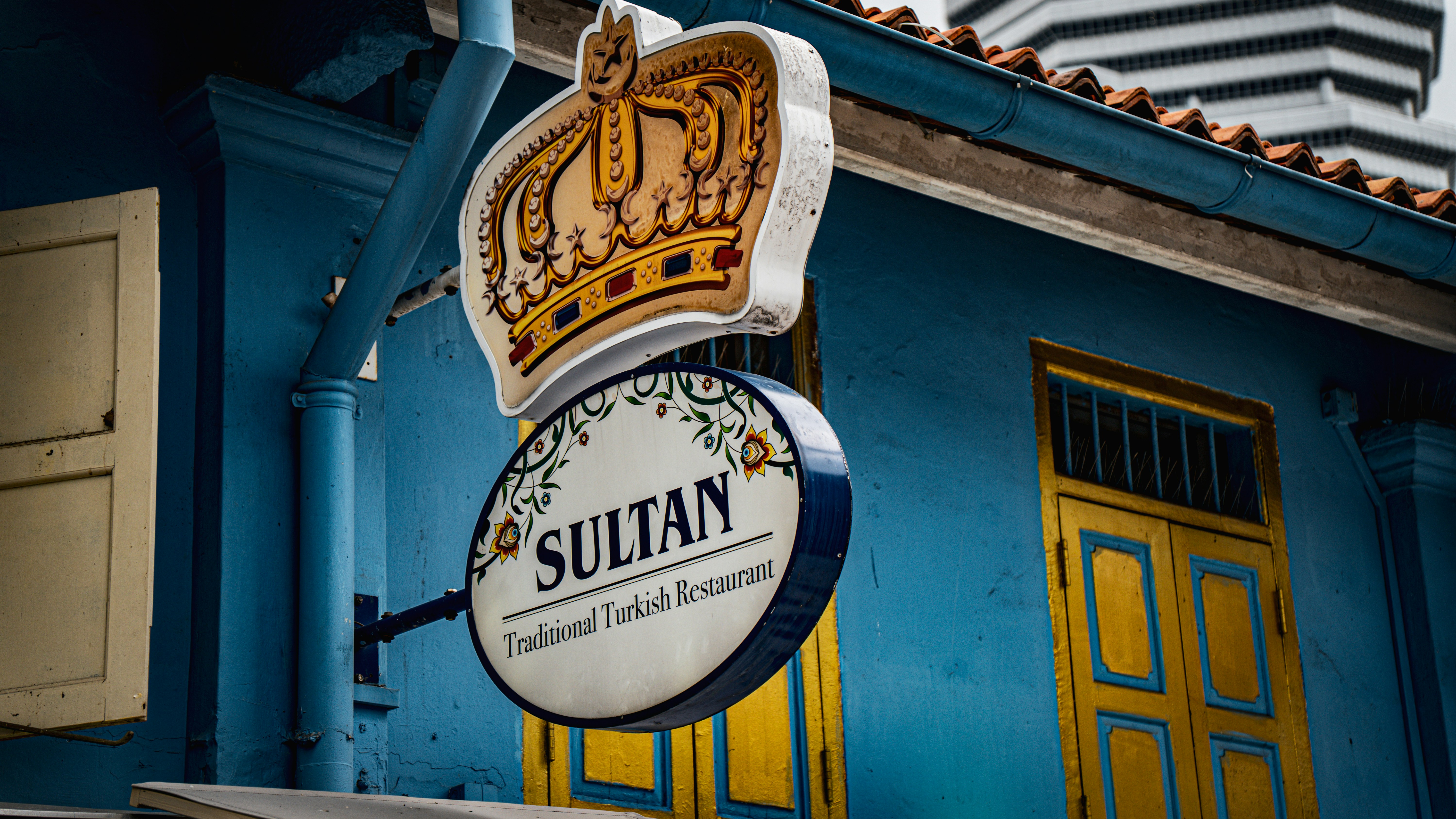 Blaues Gebäude mit "Sultan"-Restaurantschild und goldener Krone.