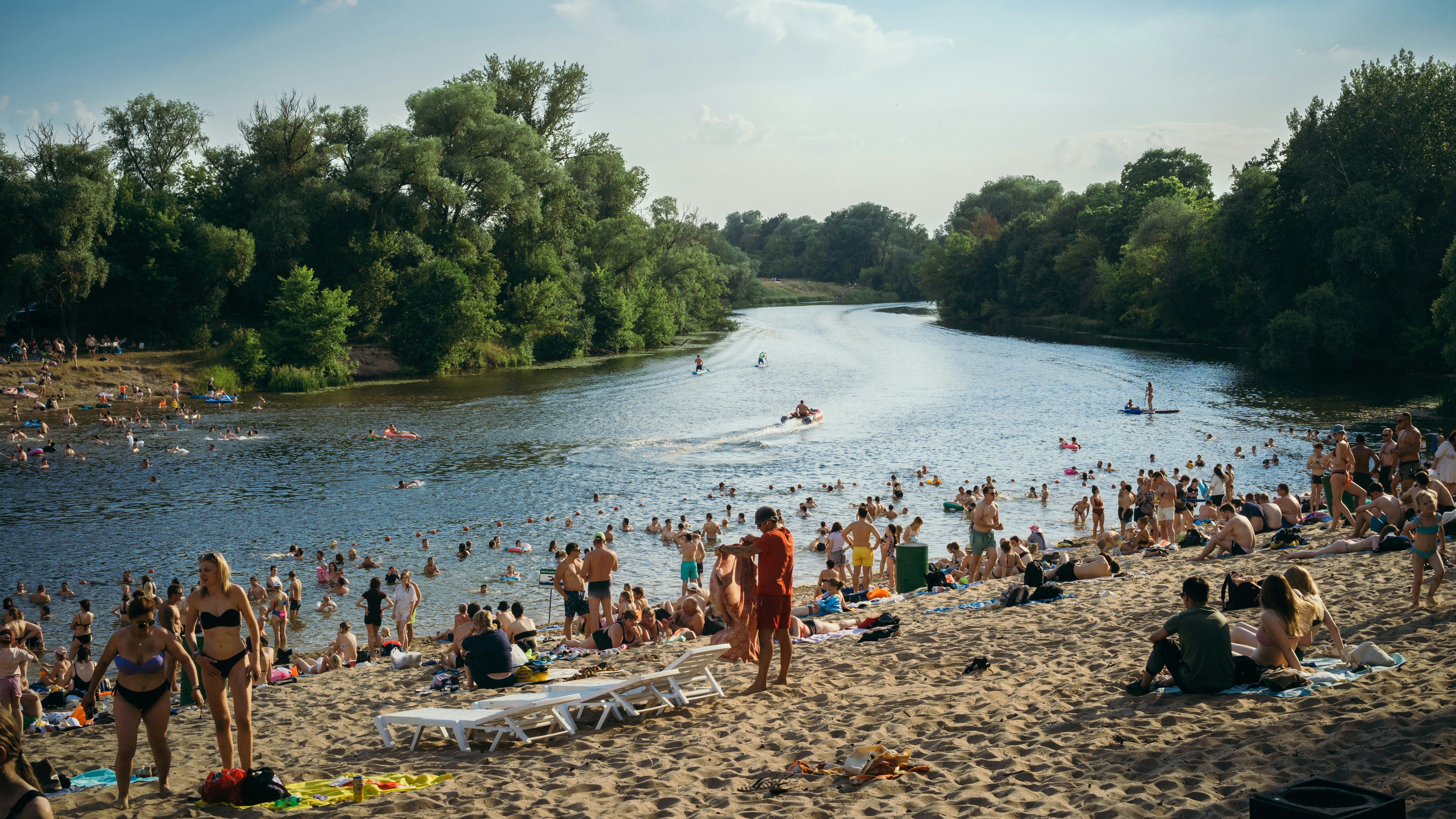 Viele Menschen schwimmen und entspannen an einem sandigen Flussstrand.