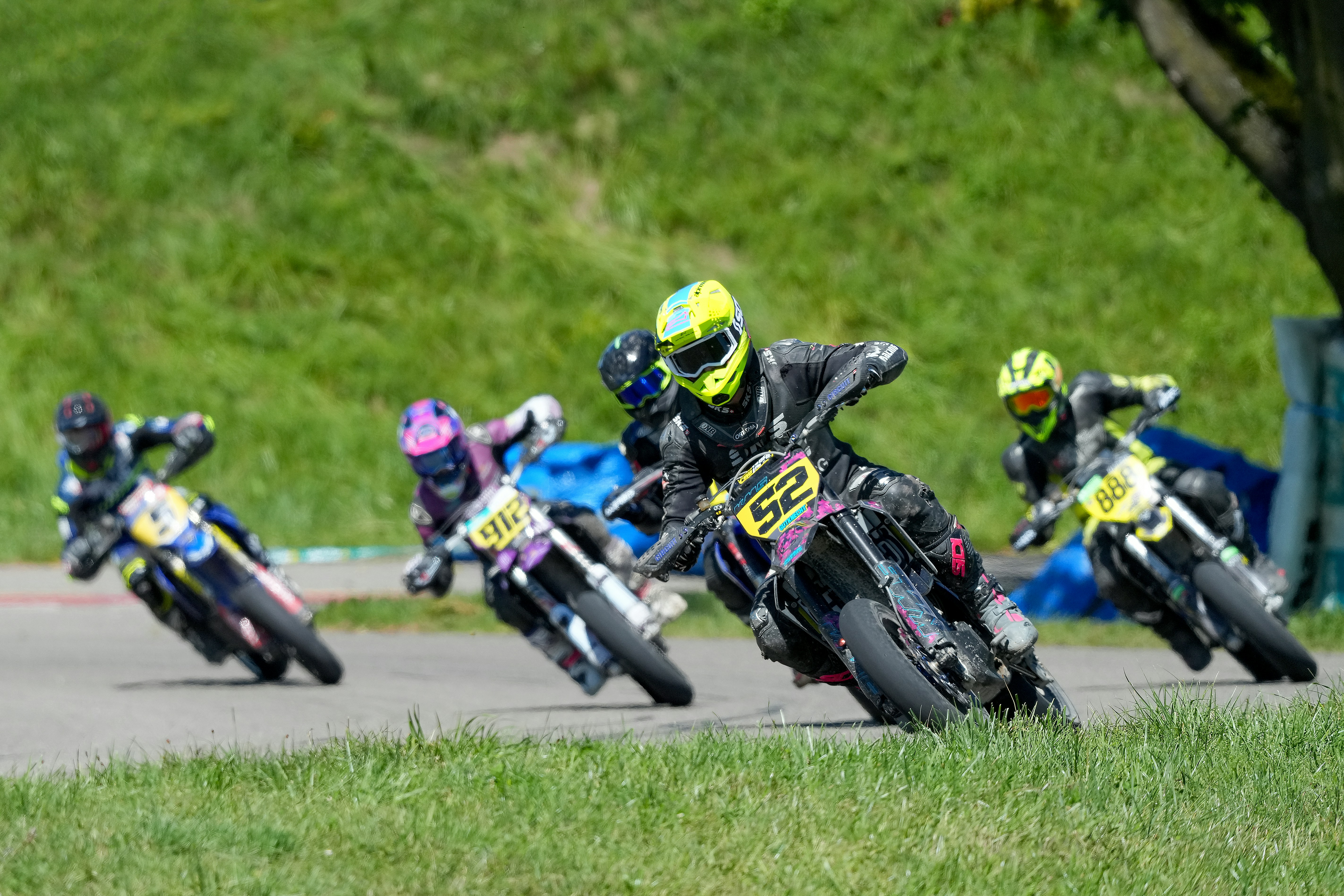 Motorcyclists racing on a track, leaning into a turn.