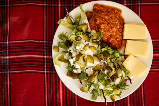 Plate of salad, red stew, and cheese.