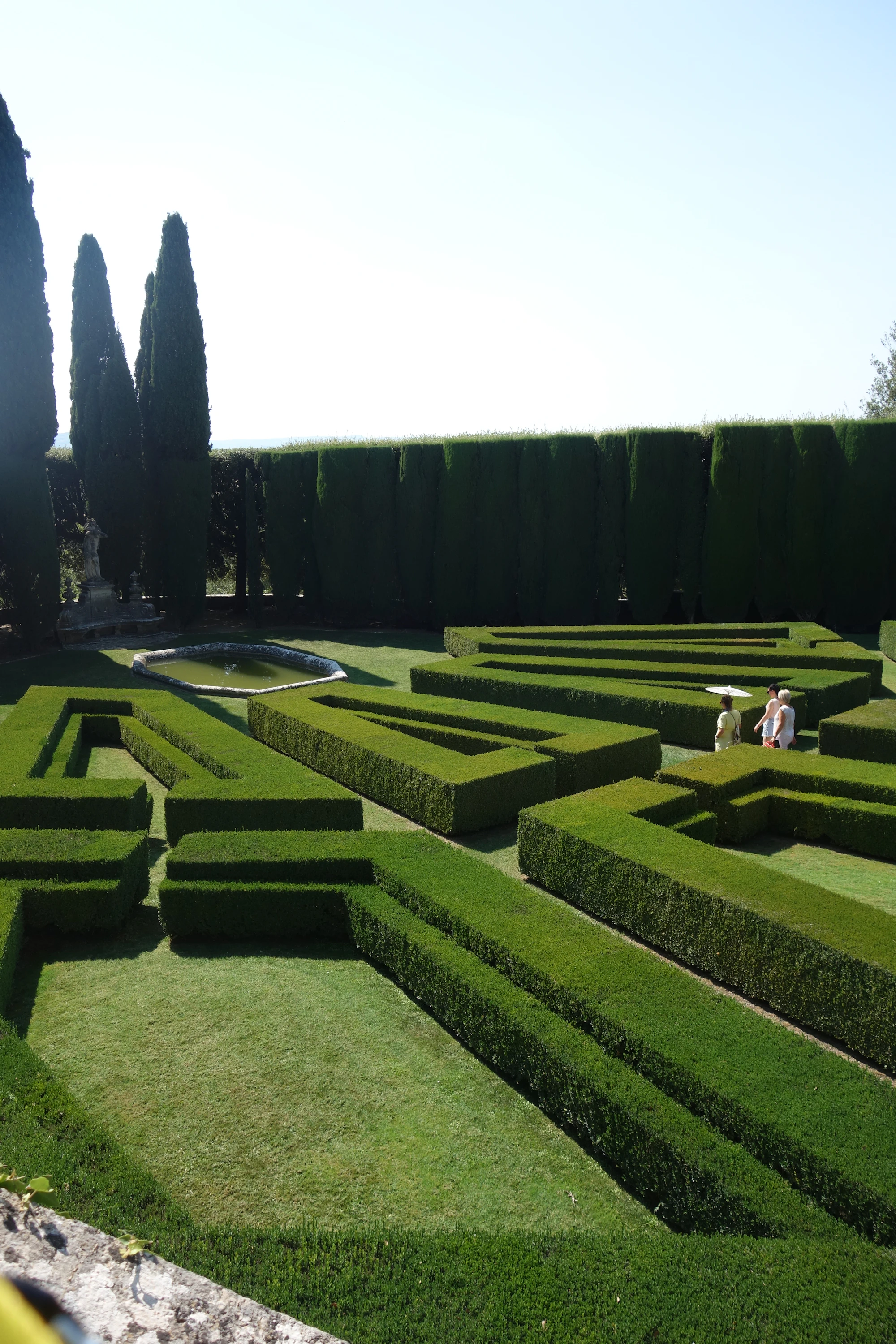 A formal garden with tightly clipped geometric hedges and a gravel path.