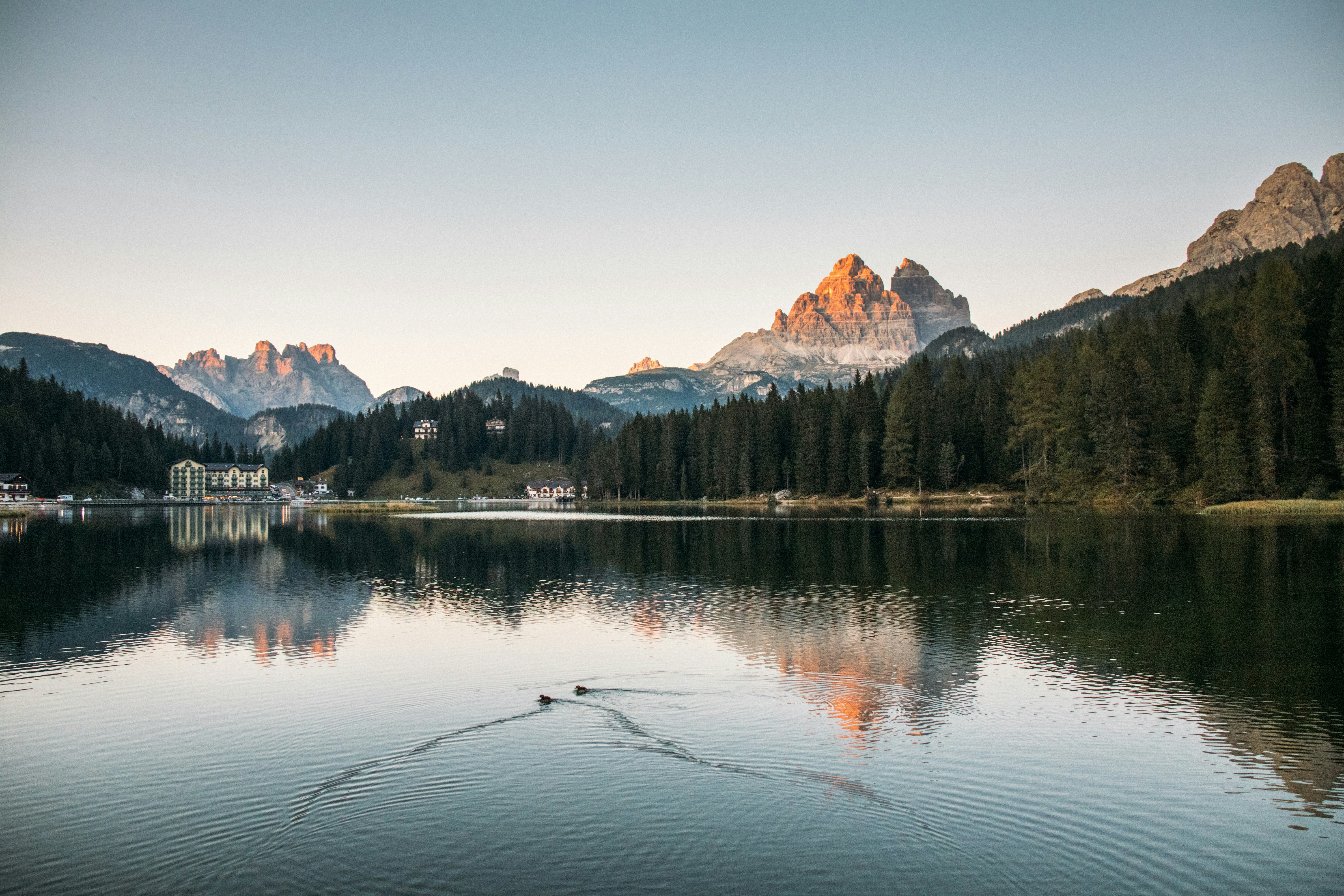 Serene mountain lake reflecting sunlit peaks and forest.
