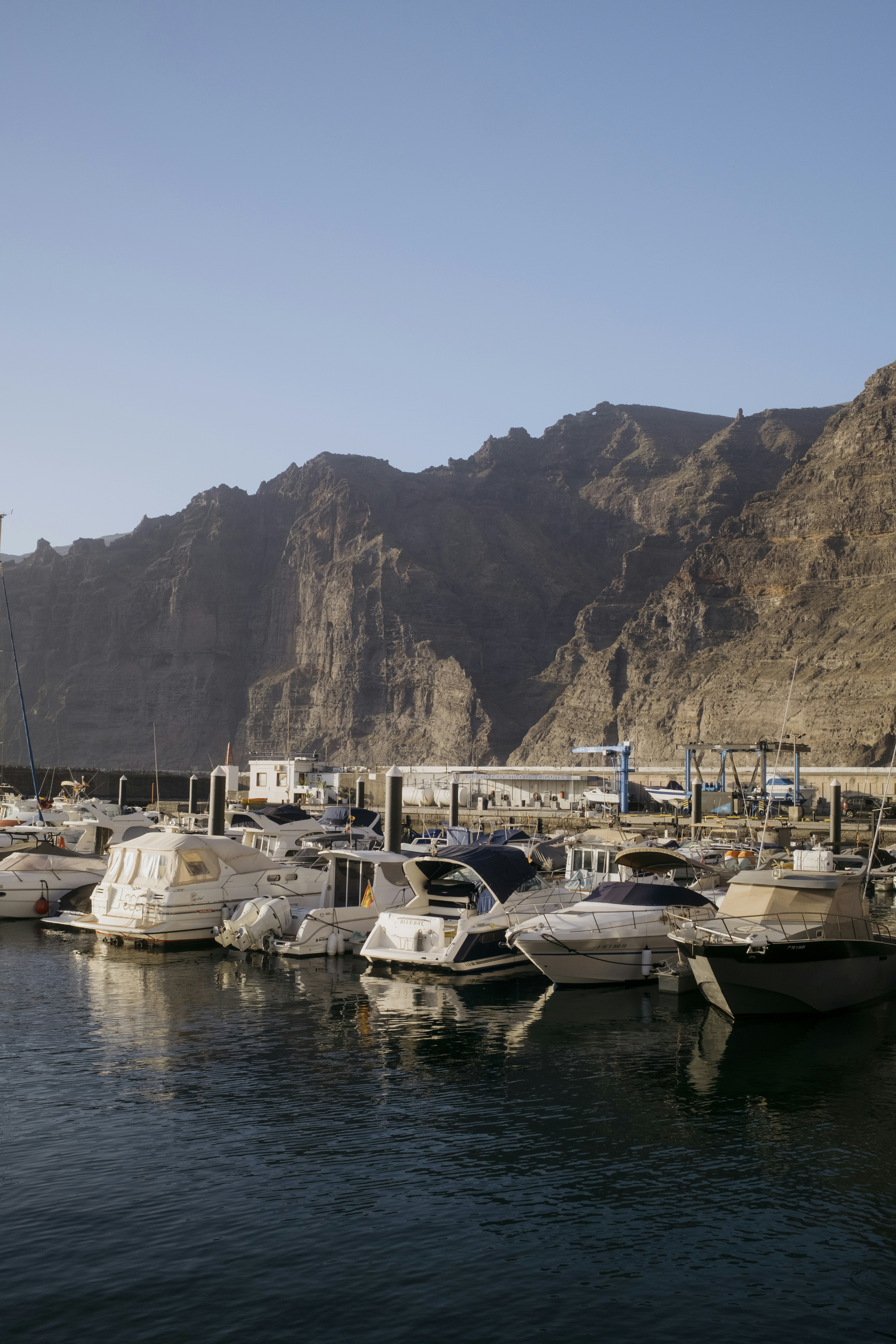 Marina filled with boats against a backdrop of rugged mountains.