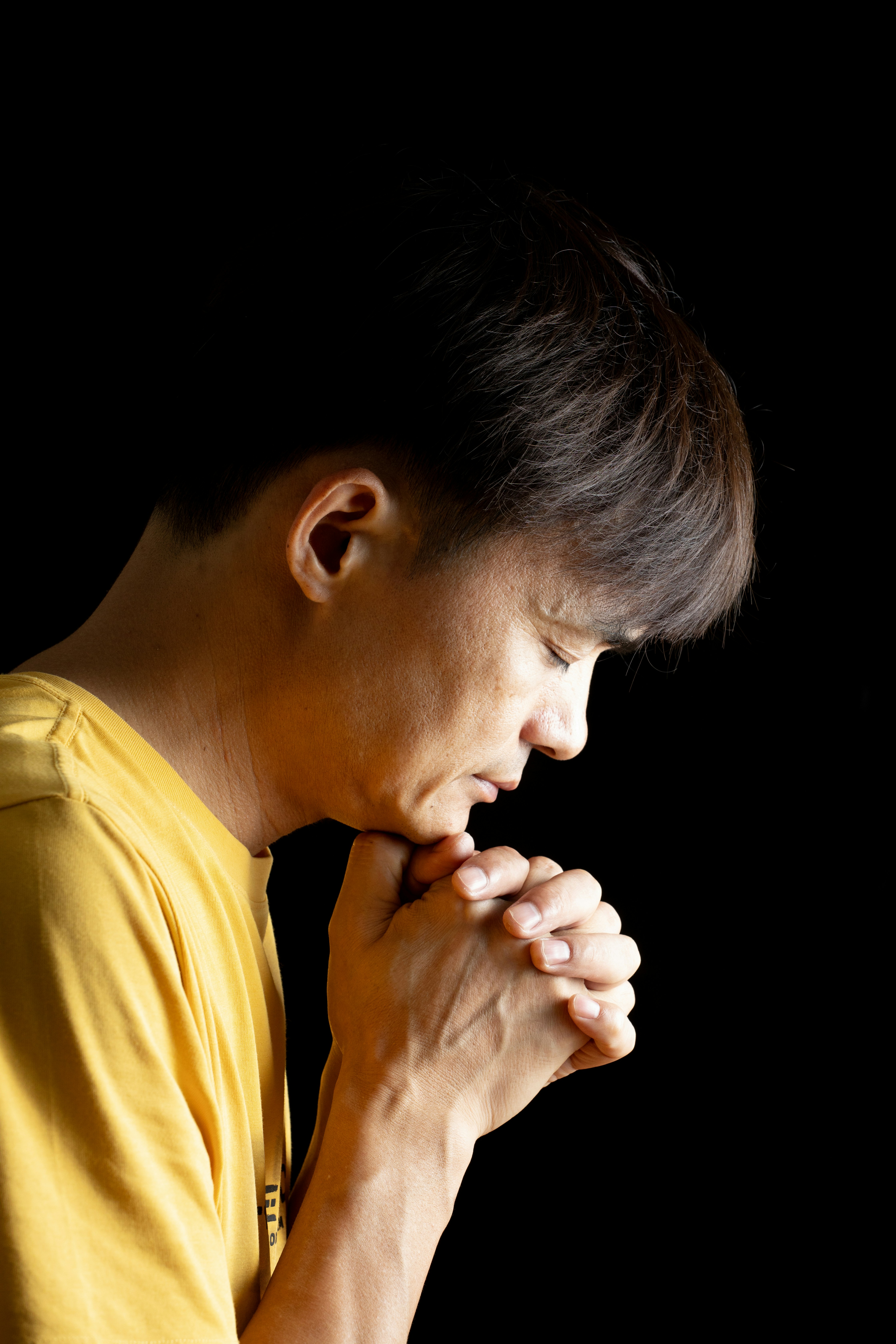 Man with bowed head and clasped hands praying