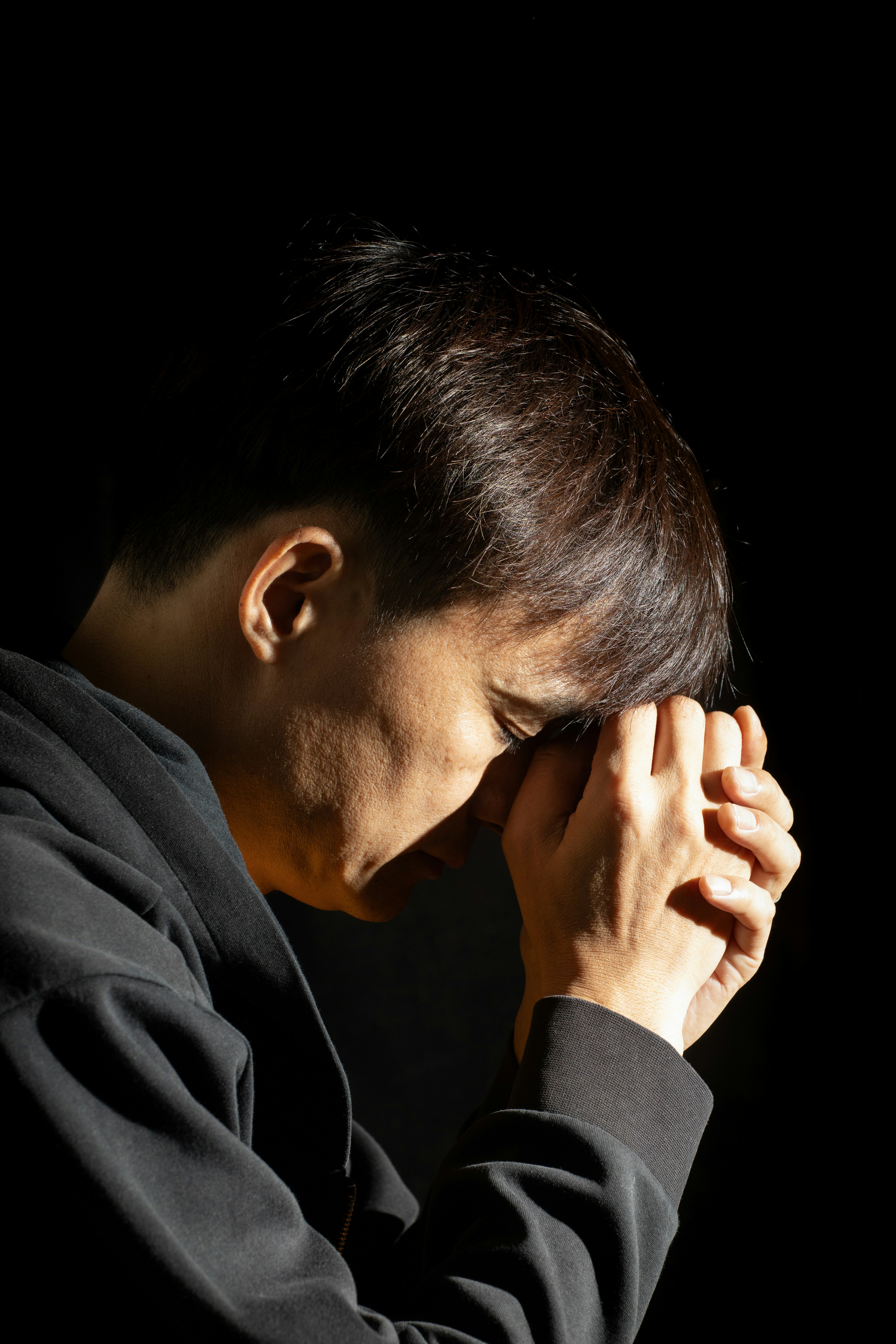 A person bowing their head with clasped hands.