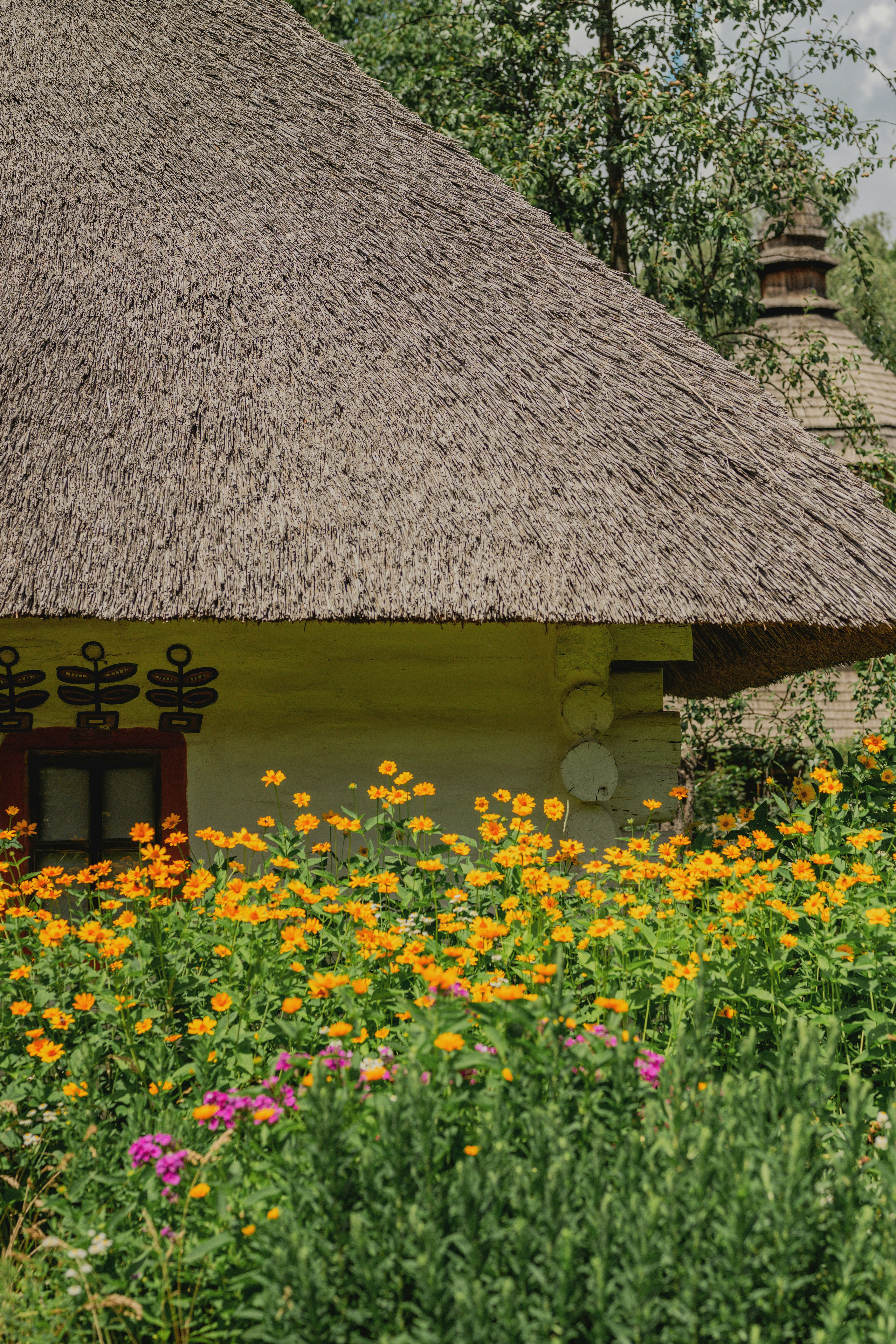 Uma casa tradicional com telhado de palha e flores vibrantes.