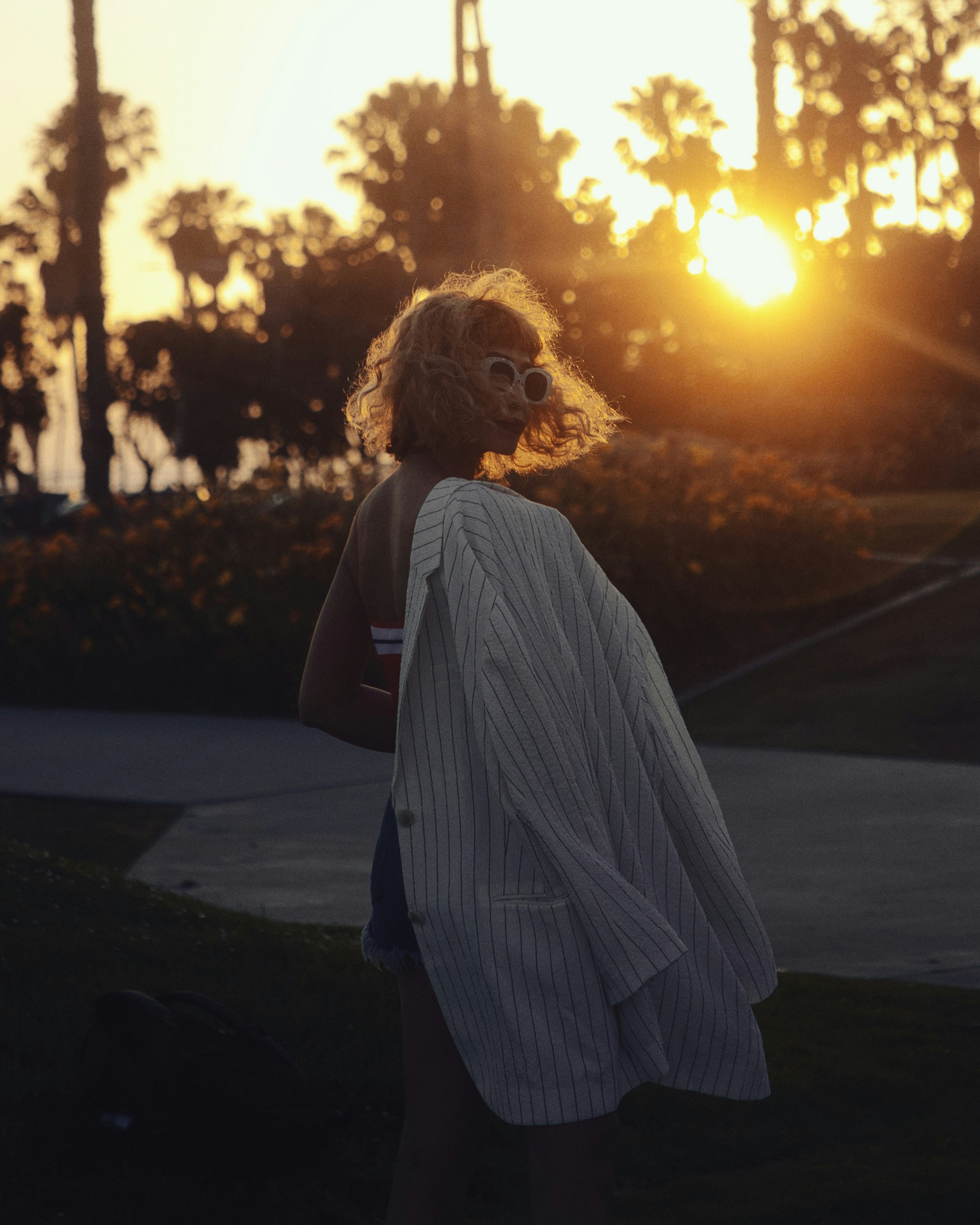 Woman in silhouette holding jacket during sunset