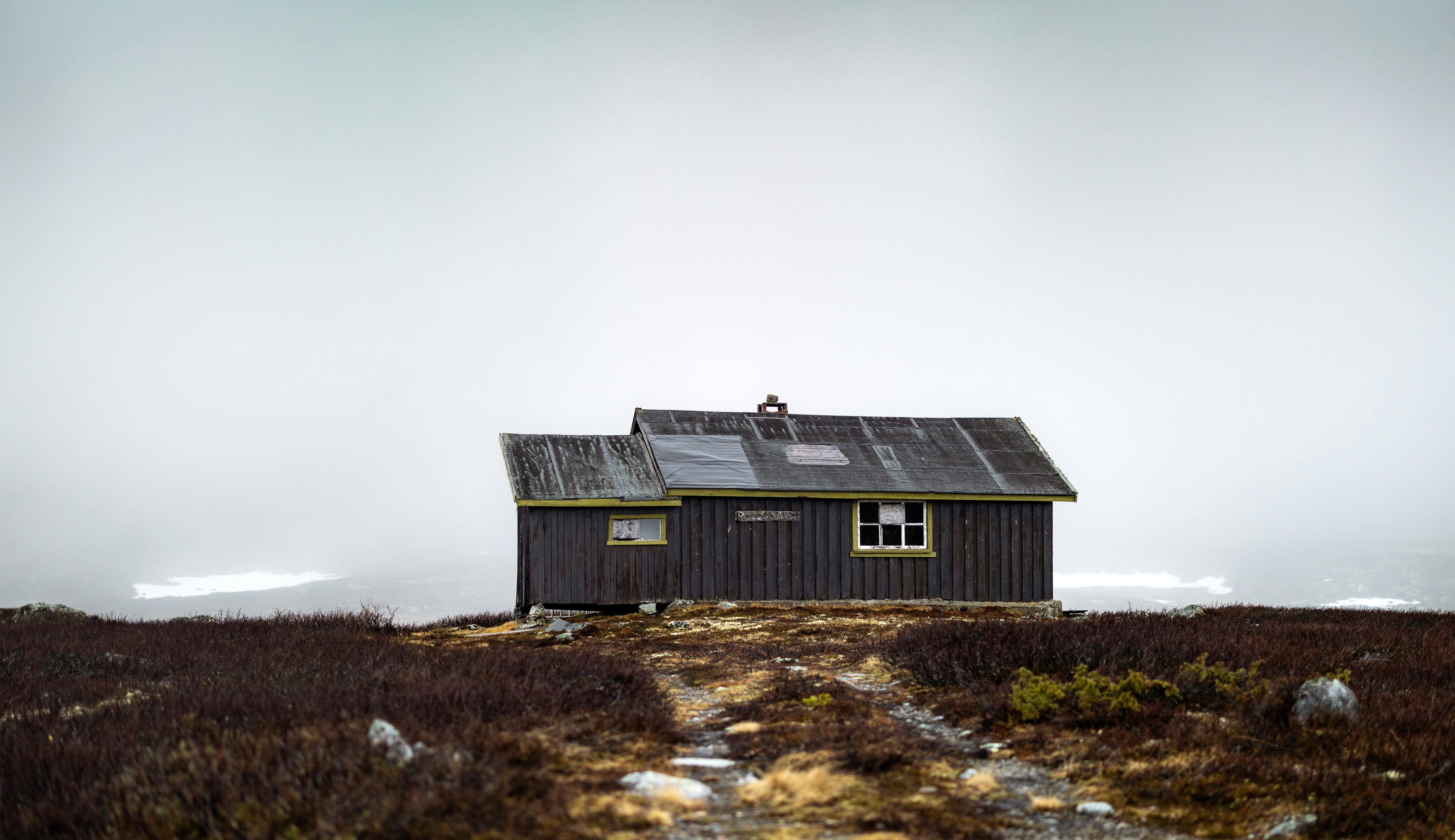 Isolated wooden cabin on a hill under an overcast sky.