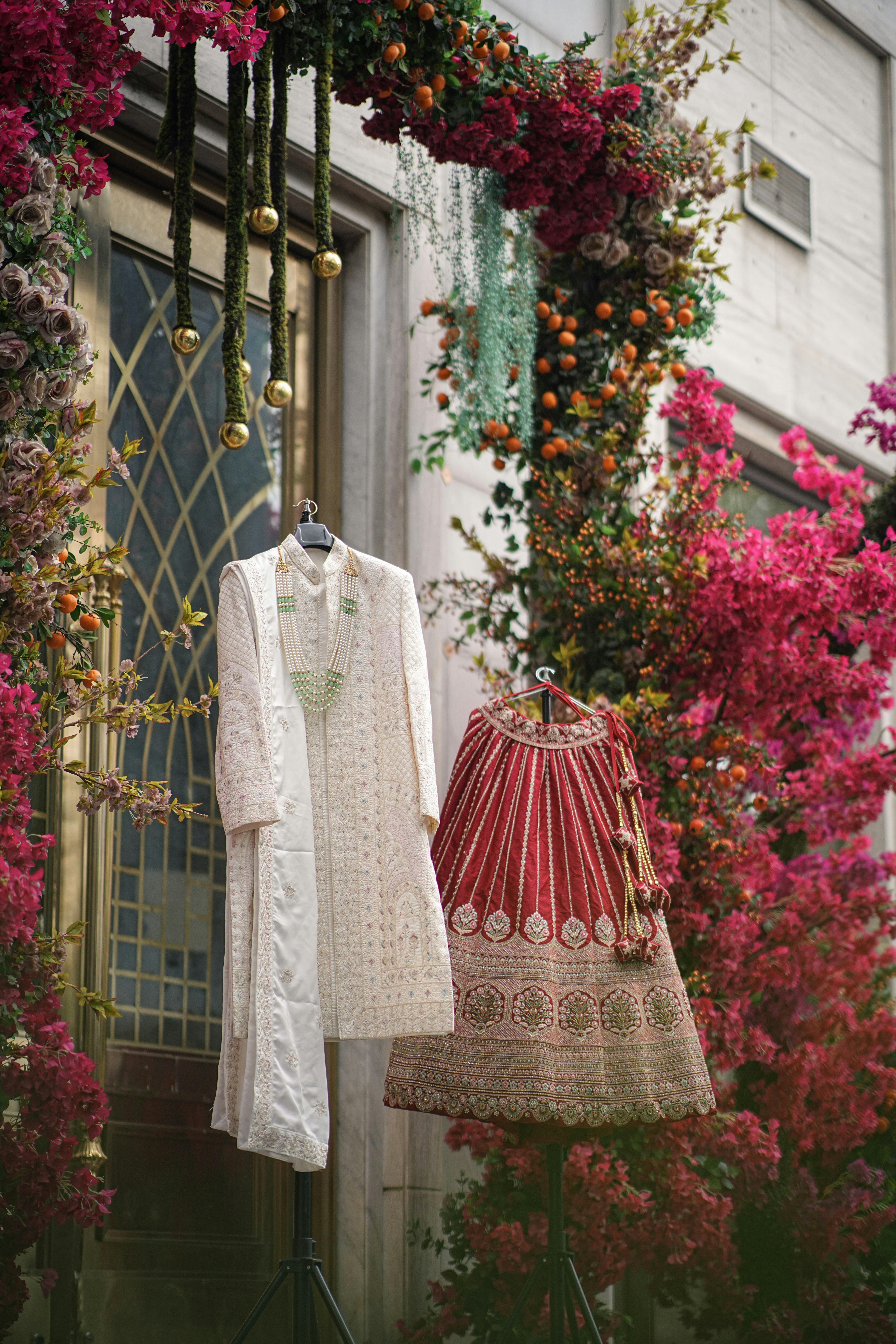 Traditional indian wedding outfits displayed amidst colorful floral decorations.