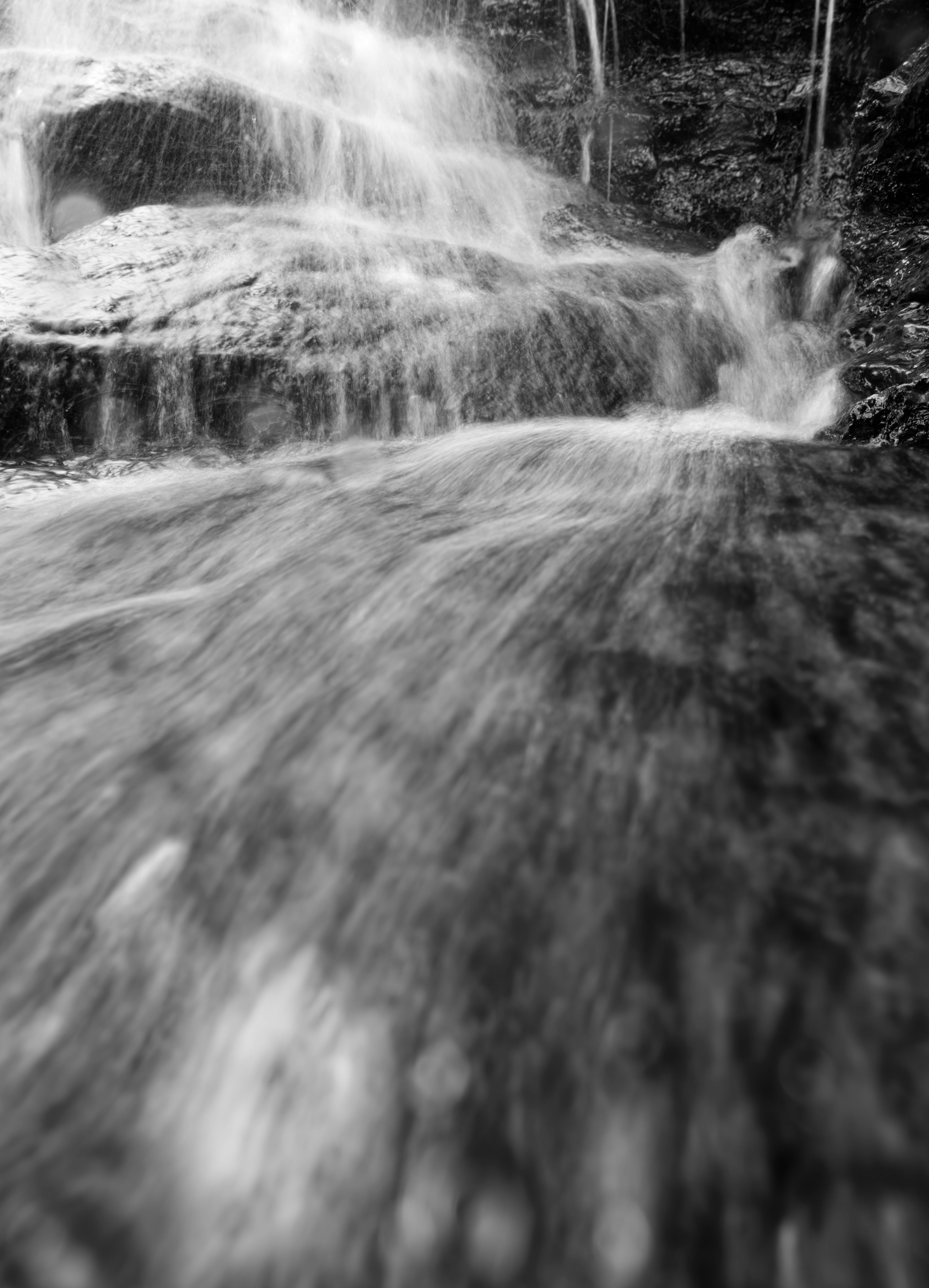Cascate in bianco e nero cadono sulle rocce con lunga esposizione.