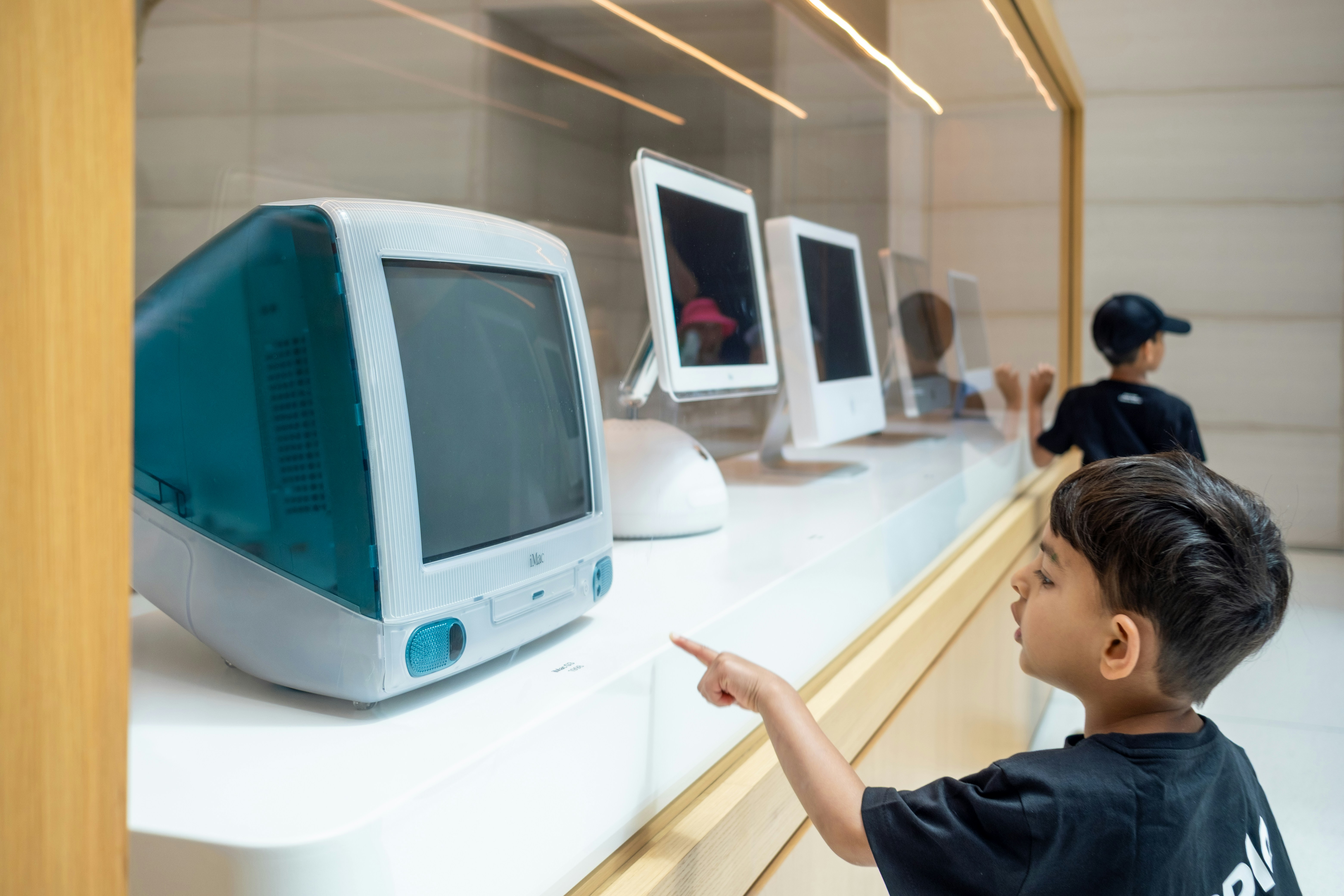 Young boy points at vintage teal imac computer display.