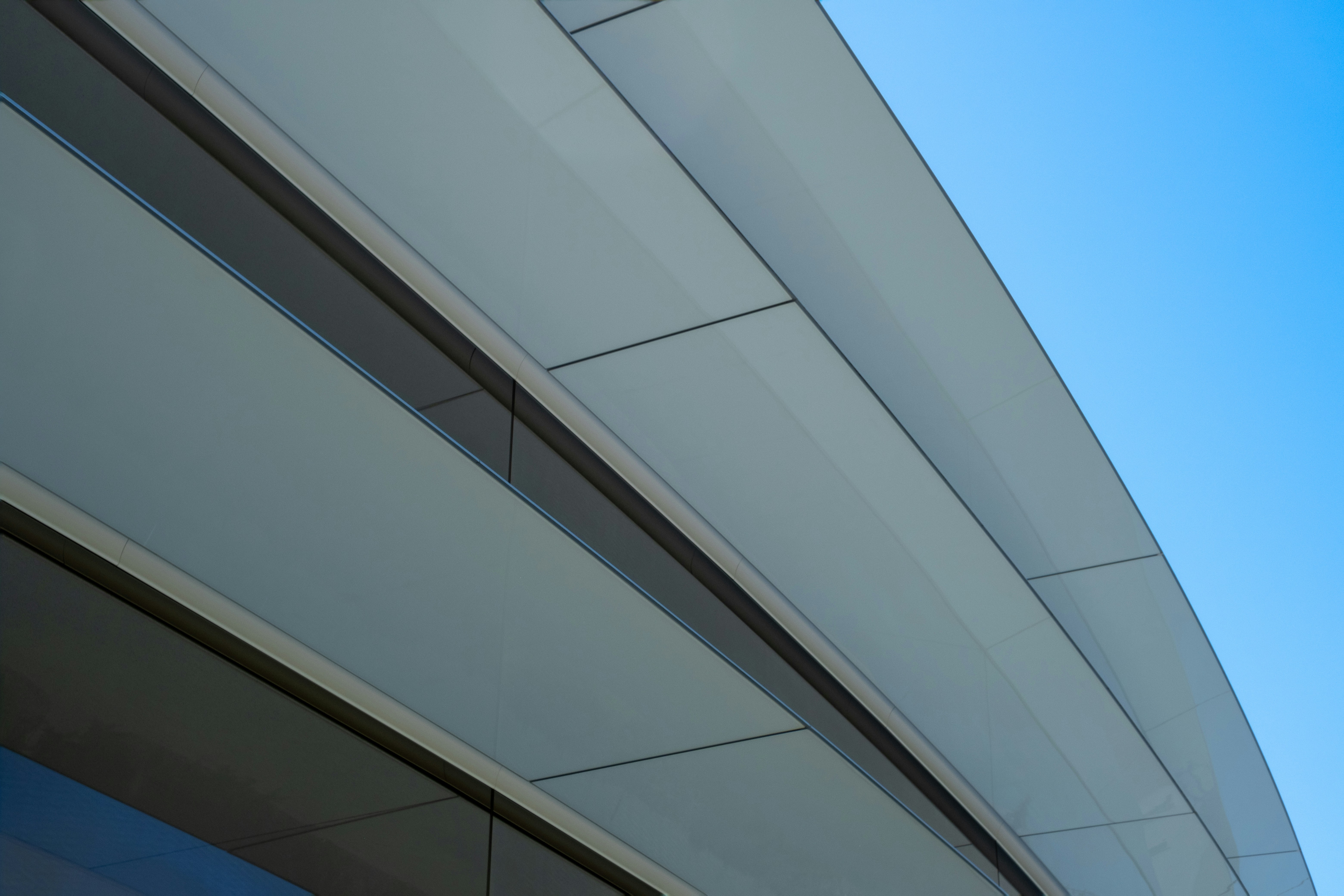 Modern building facade with curved lines against a blue sky.