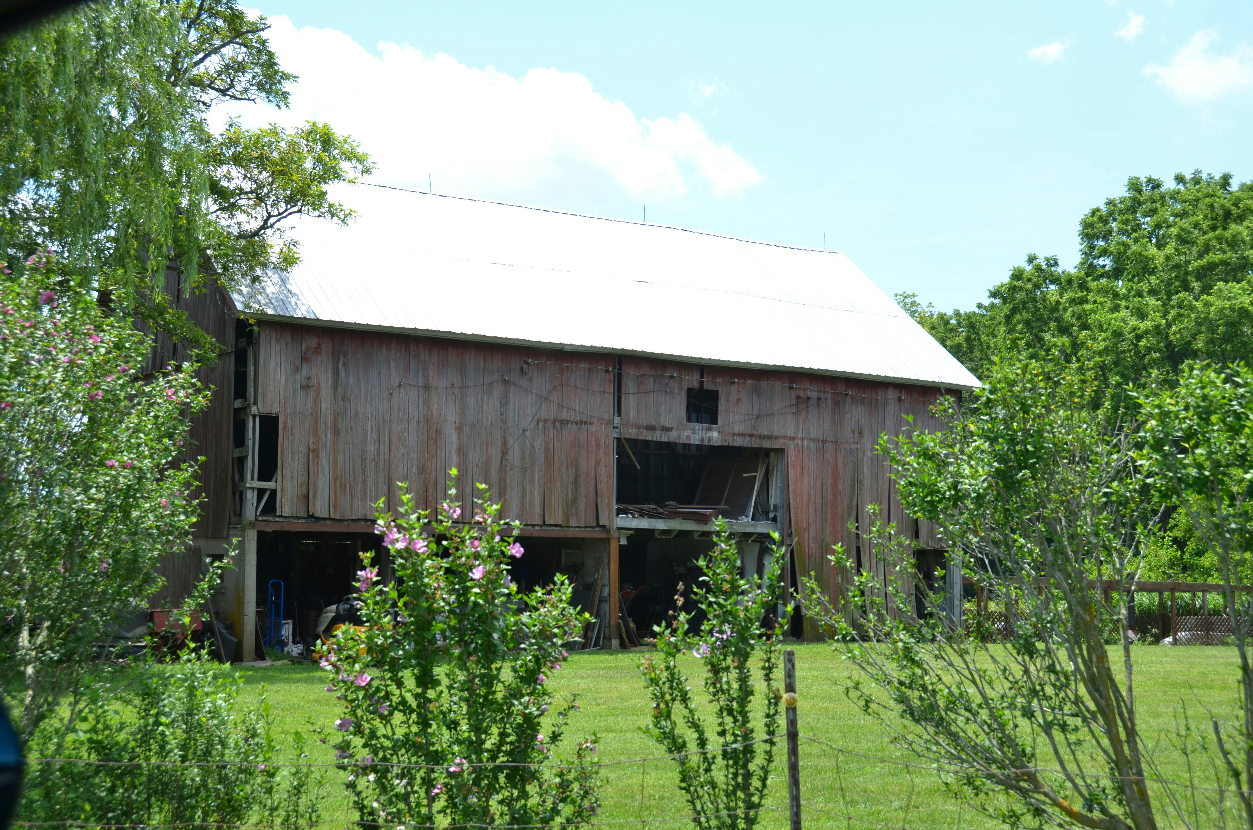 A rustic wooden barn stands in a green field.