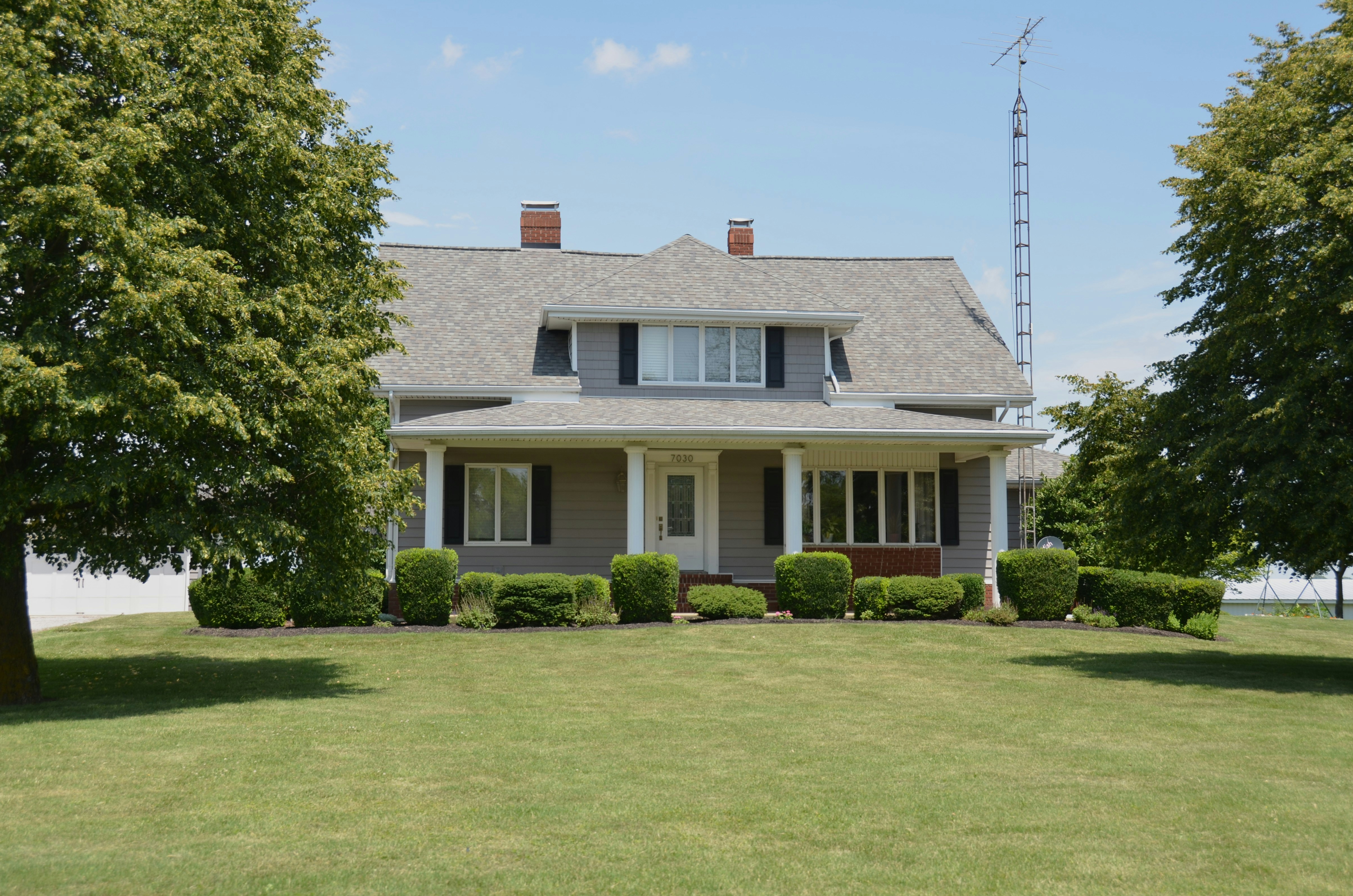 A traditional Southern house with a wraparound porch and shade trees, the kind of quiet residential street where Stranger Things' character homes still stand as occupied private residences