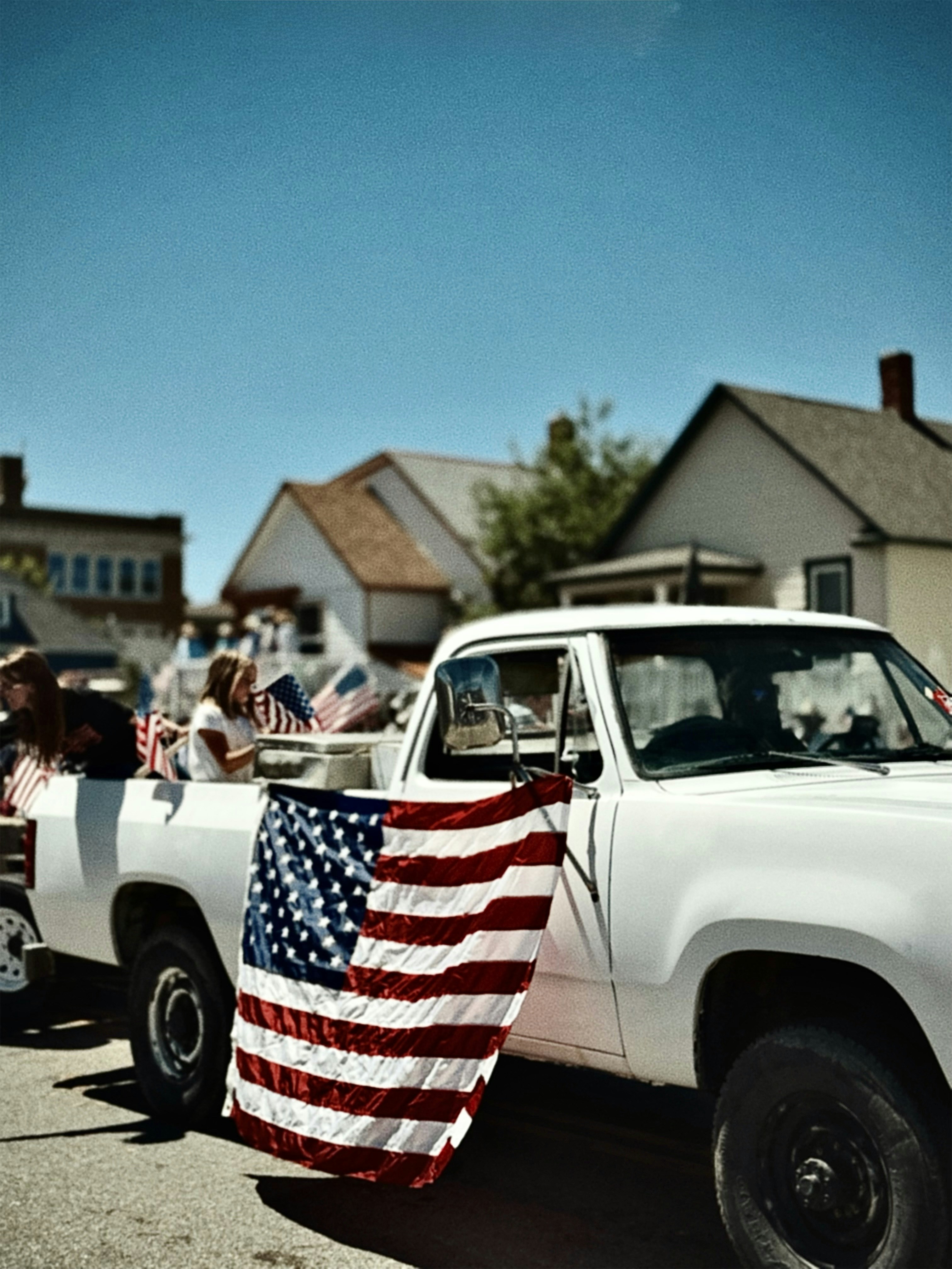 White pickup truck with american flag in a parade.