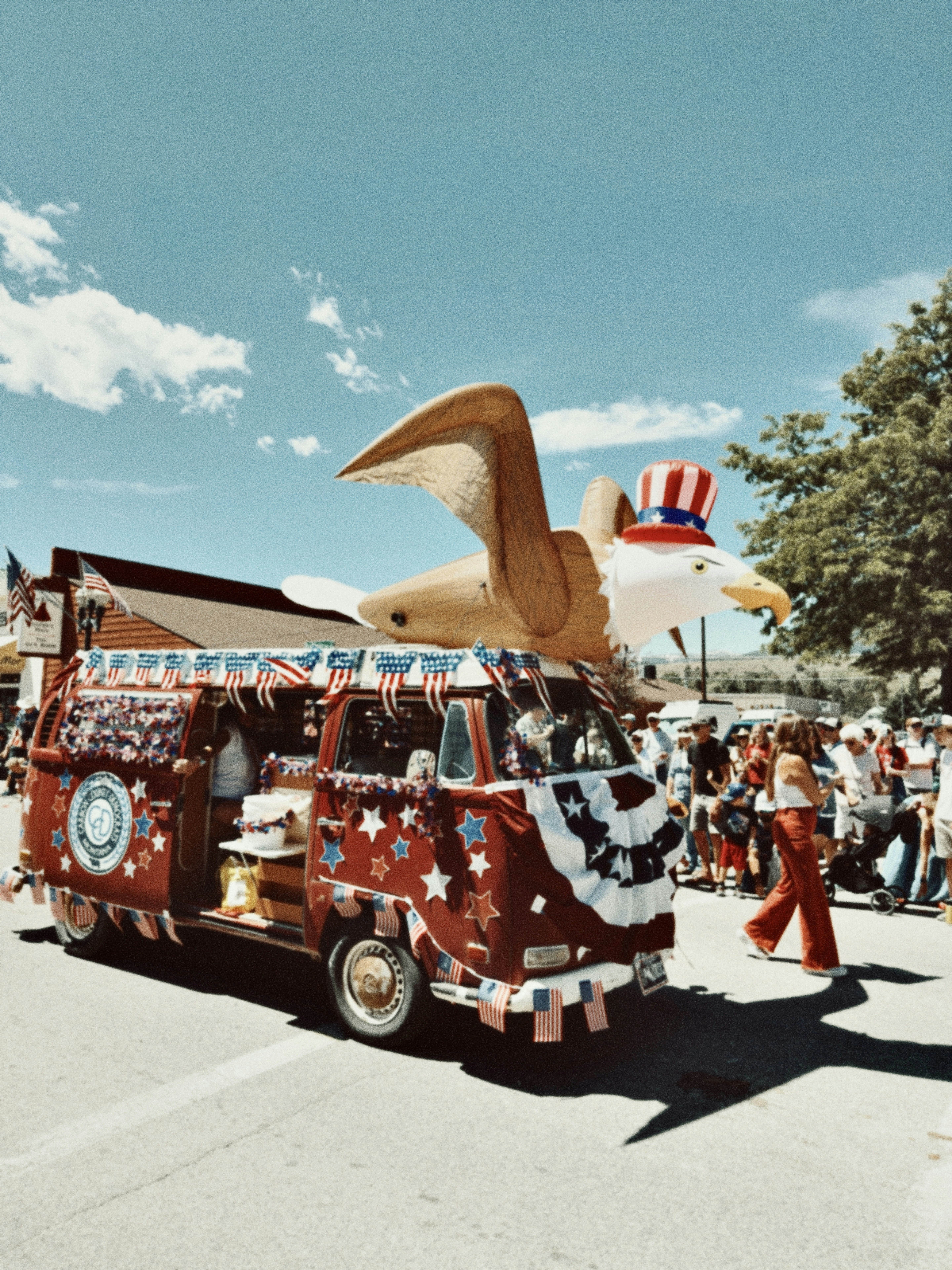 Festive van with an inflatable eagle in a patriotic parade.