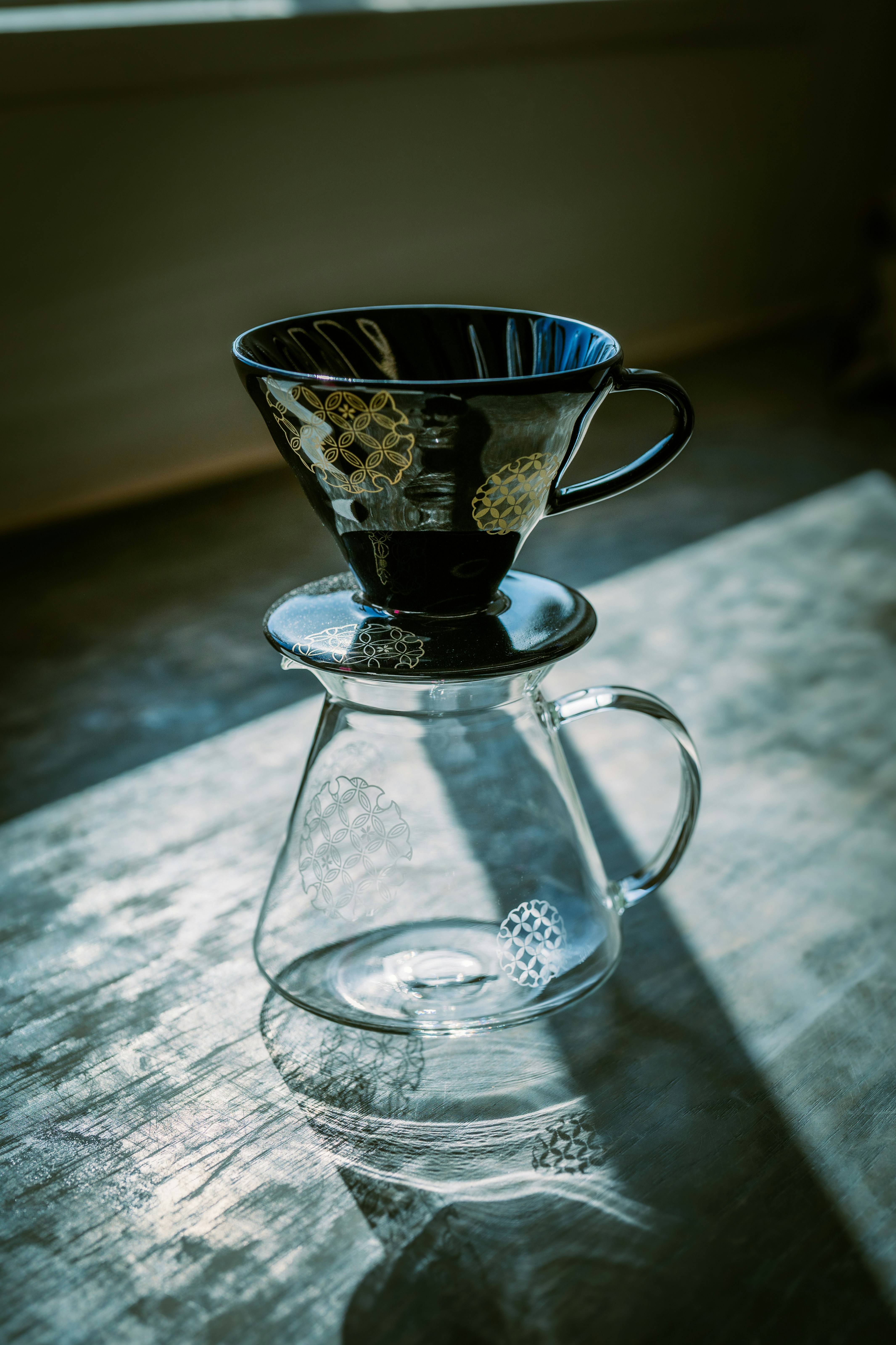 Pipes kopi keramik hitam di atas teko kaca bening.