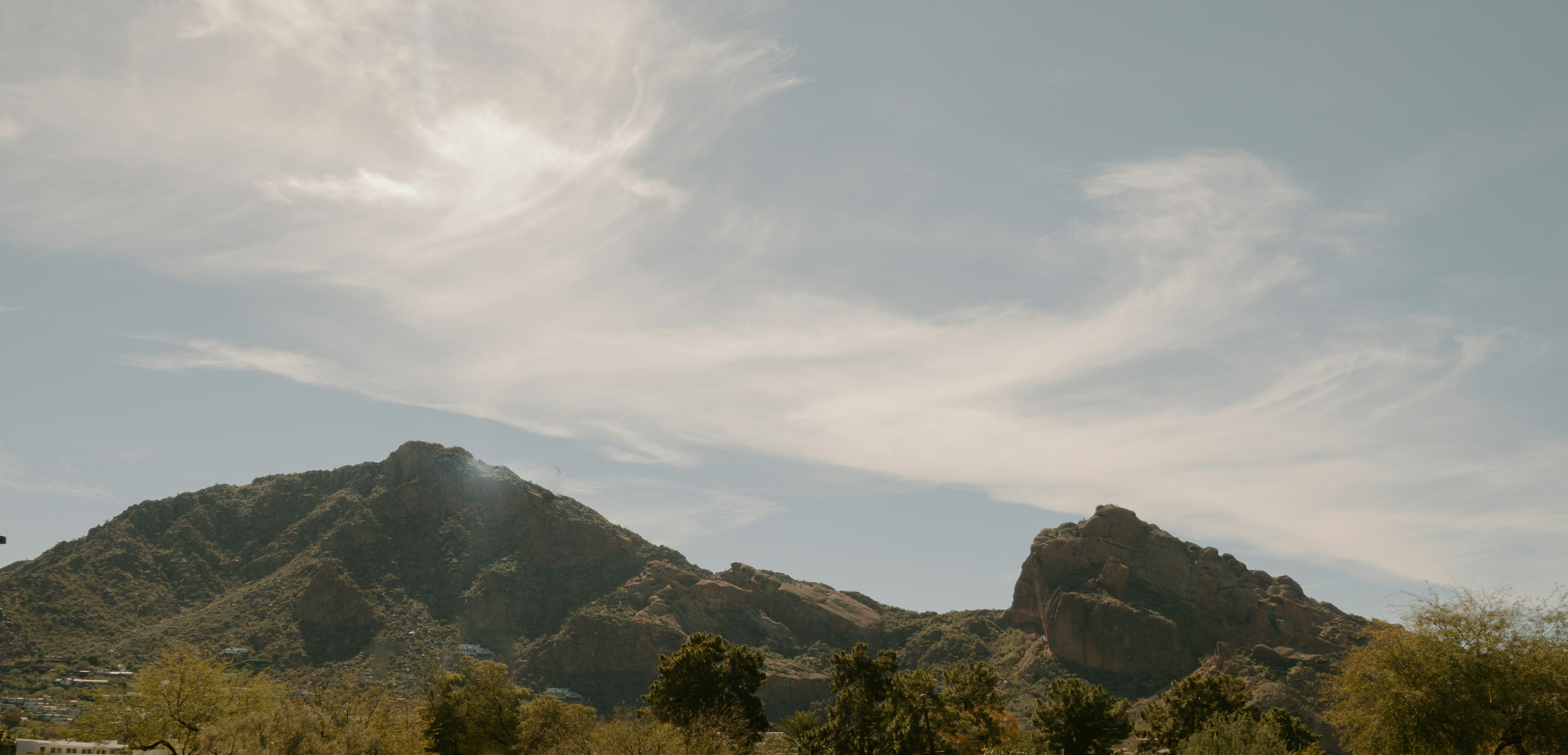Desert mountains and trees under a partly cloudy sky