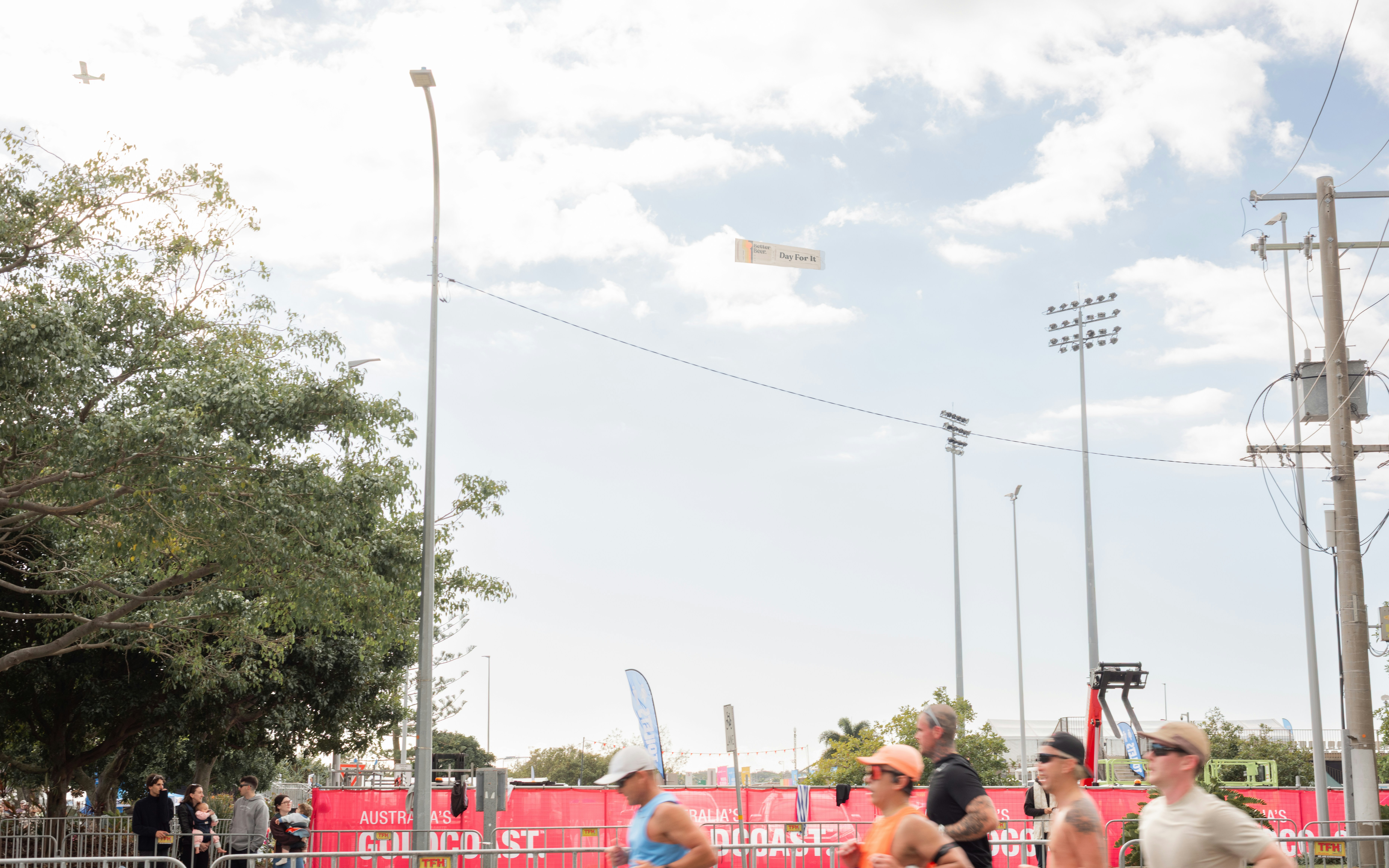 A banner plane flies over people at an outdoor event.
