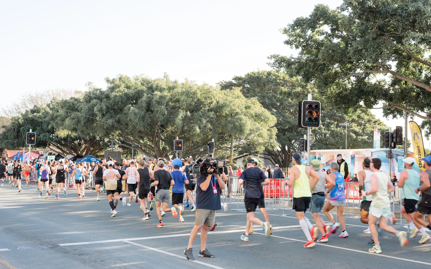 Road runners moving through the first minutes of a large race in cool morning light.