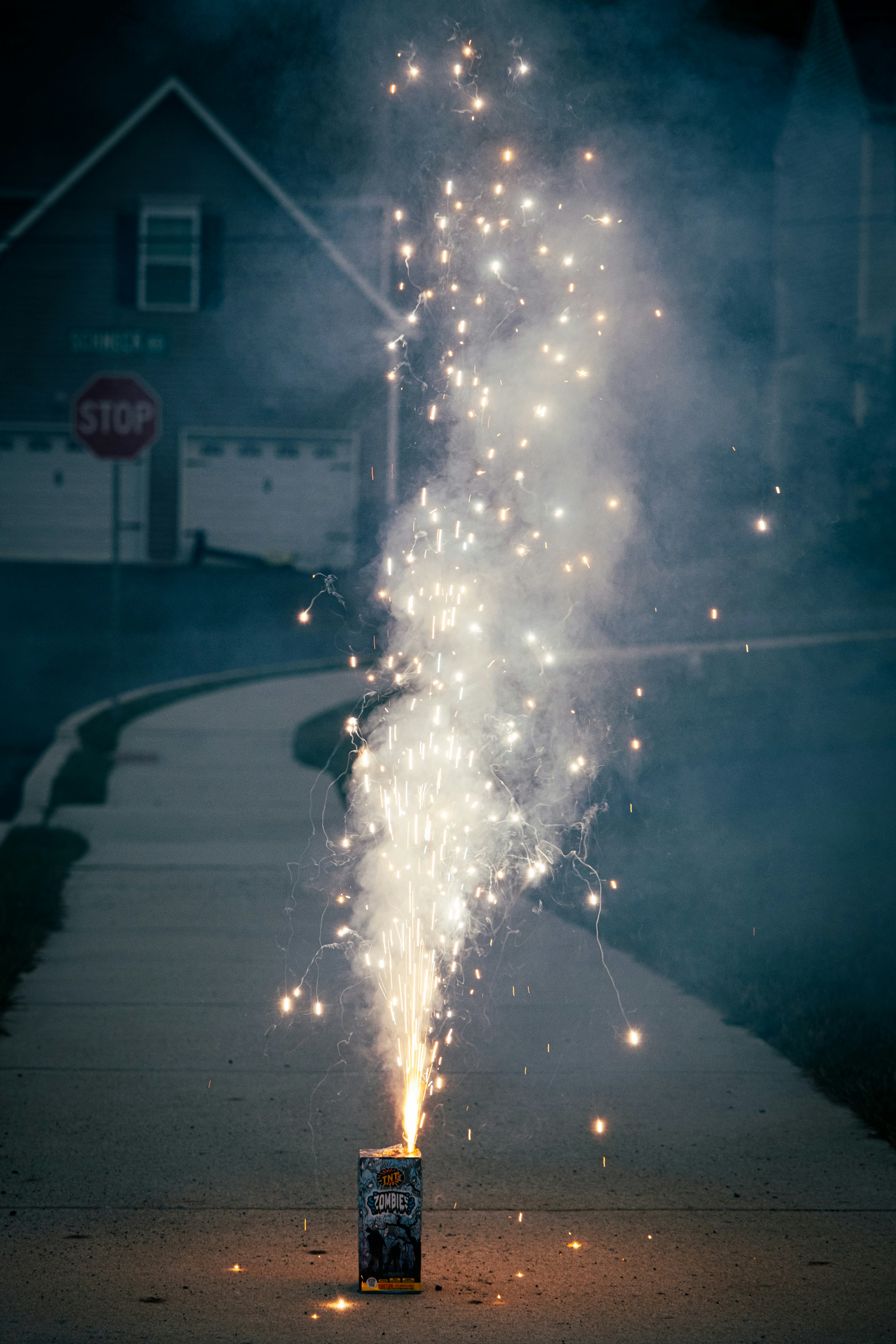 Uma fonte de fogos de artifício irrompe em uma calçada à noite.