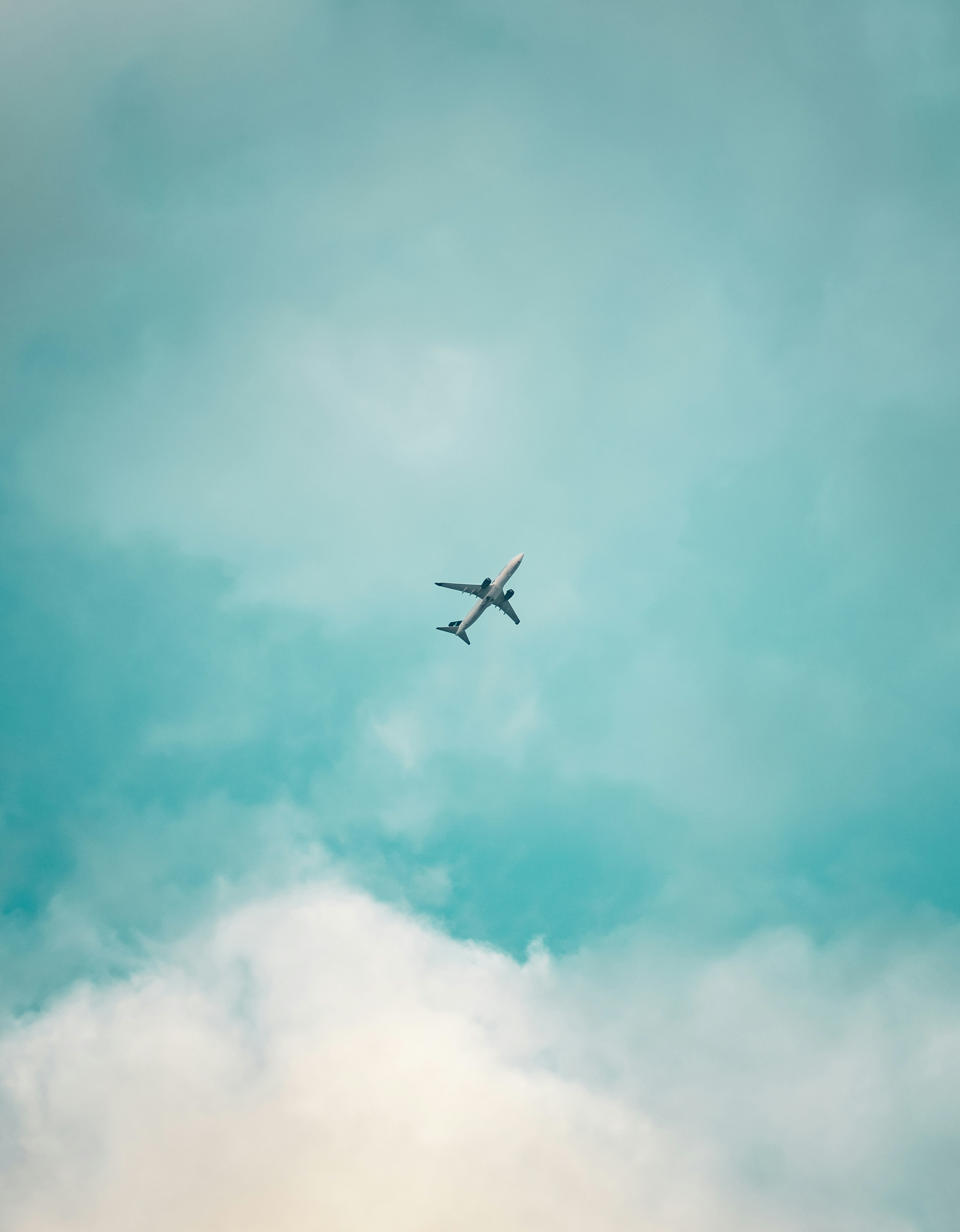Um avião voa alto em um céu azul nublado.