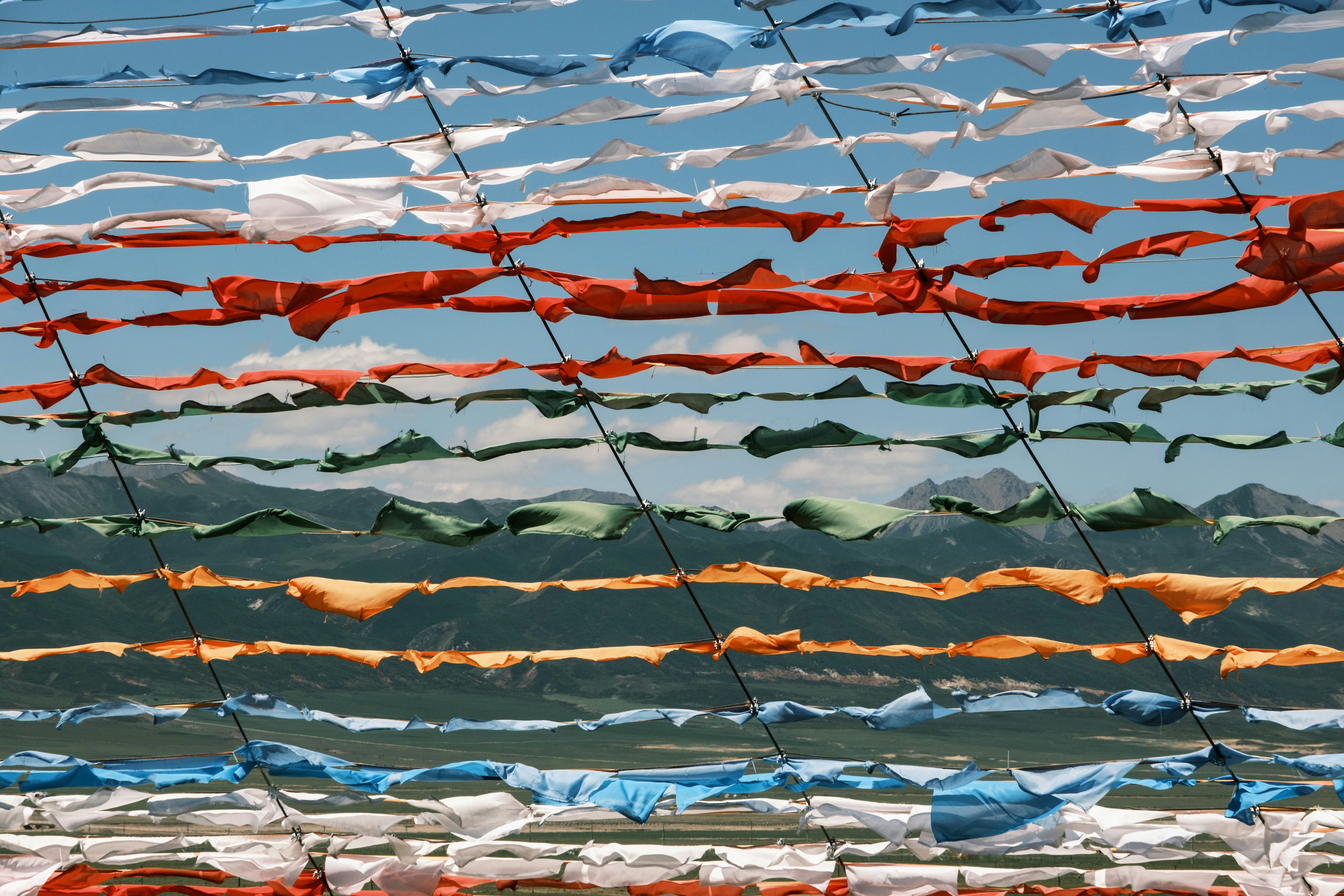 Colorful fabric strips strung horizontally against a blue sky.