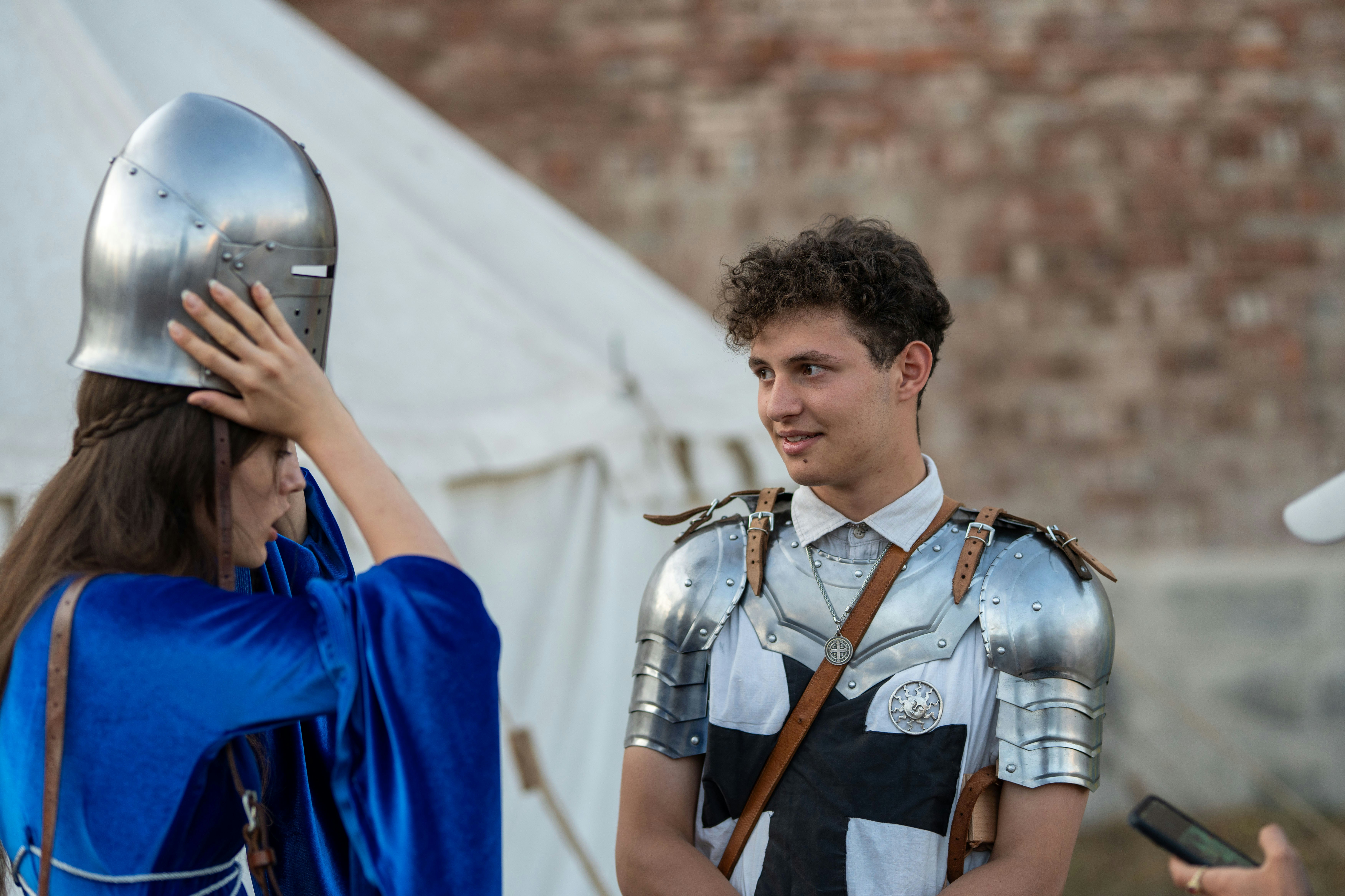 Donna aiuta un uomo in armatura a mettere un casco.