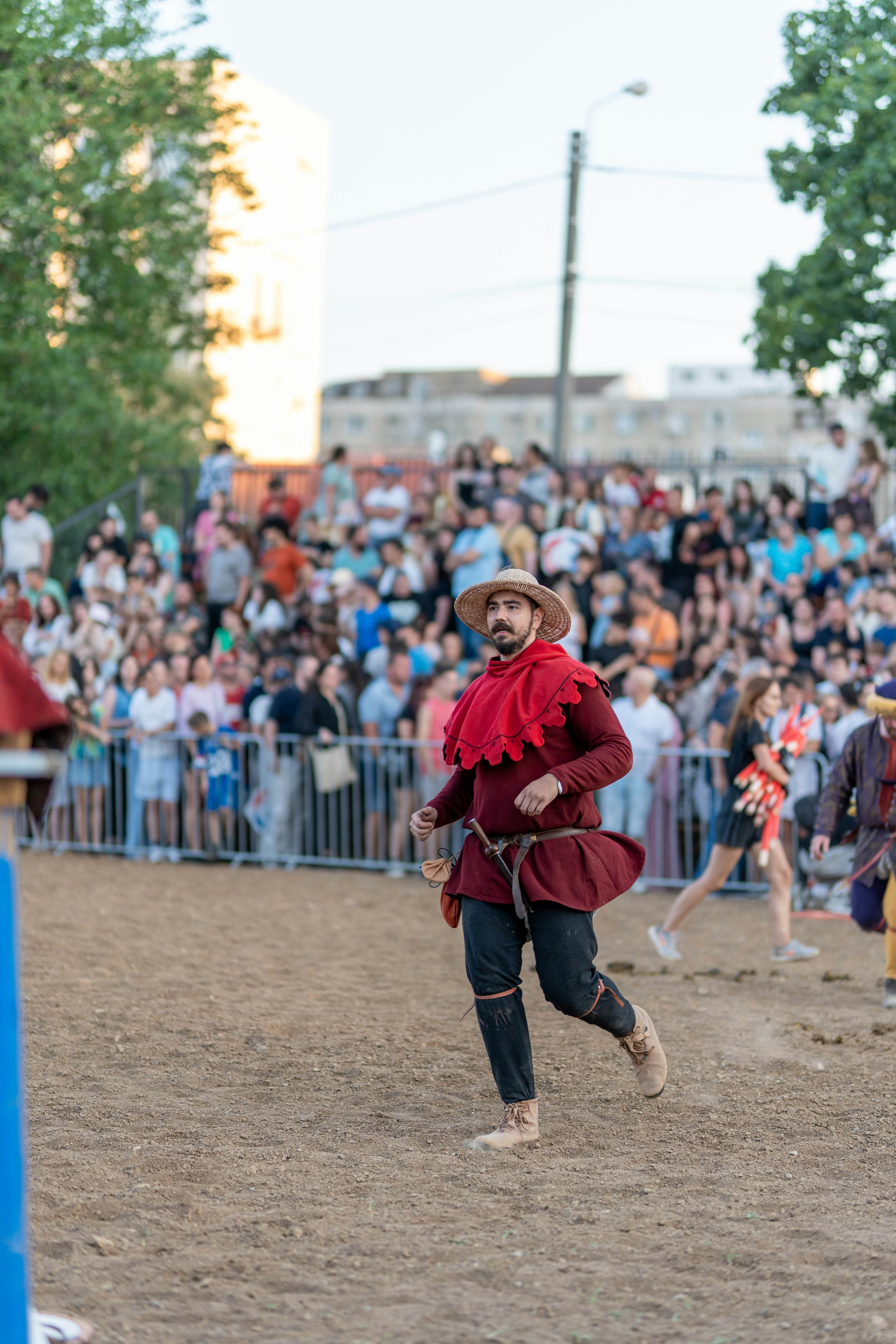 Bearded man in medieval costume running before a crowd.