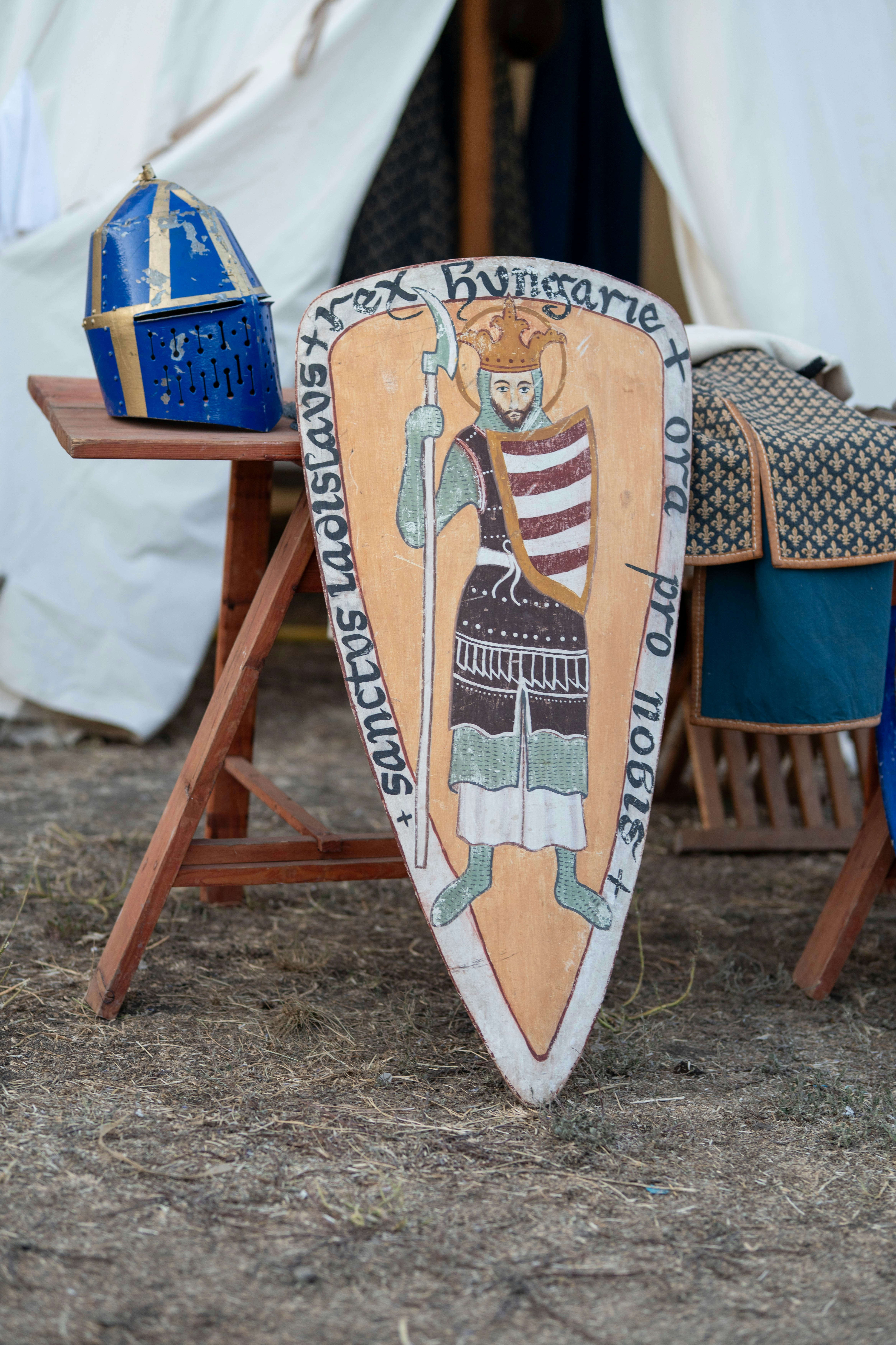 An ancient shield and blue helmet displayed outdoors.