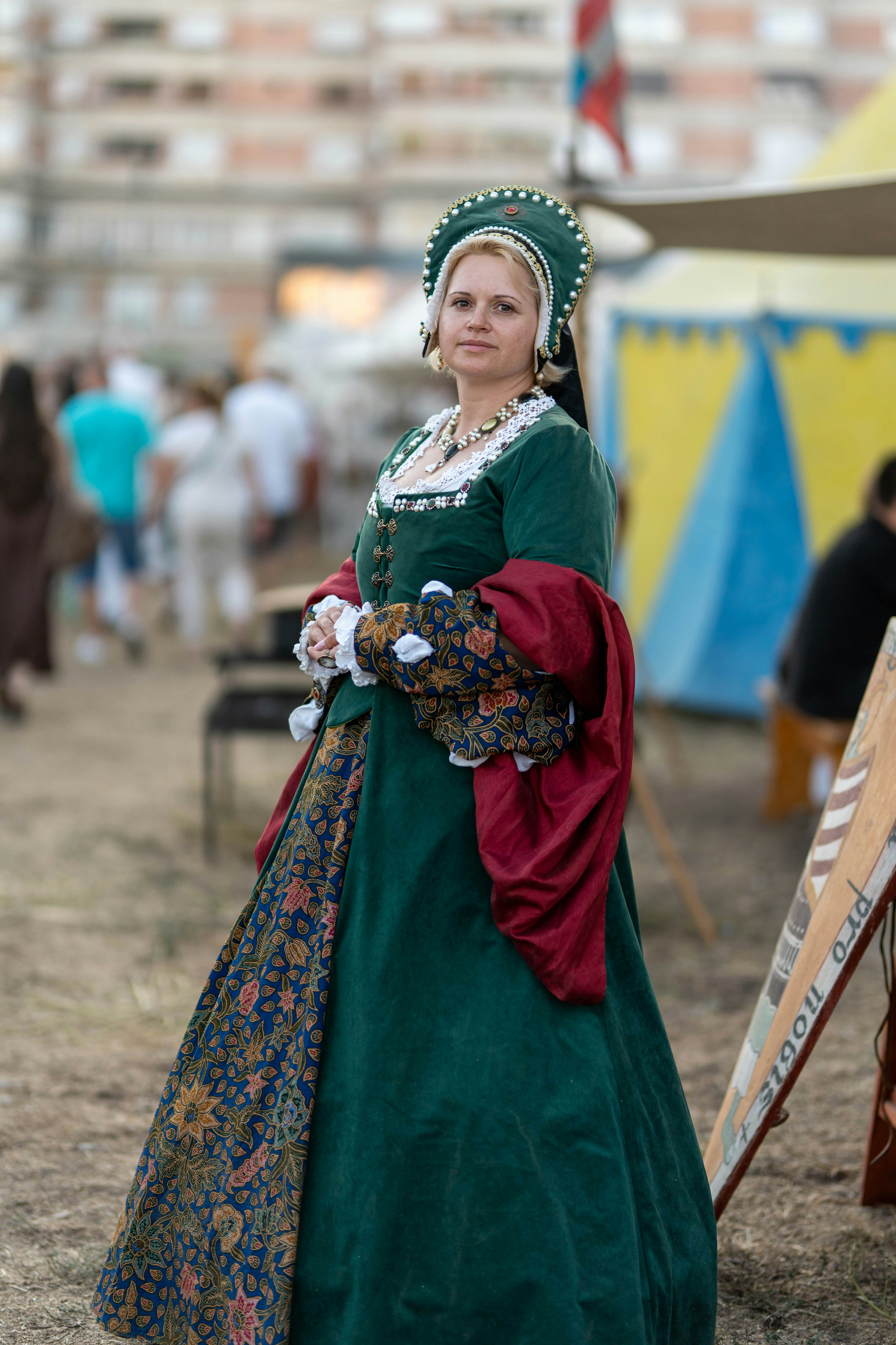 Una donna con un abito medievale verde e un elaborato copricappo.