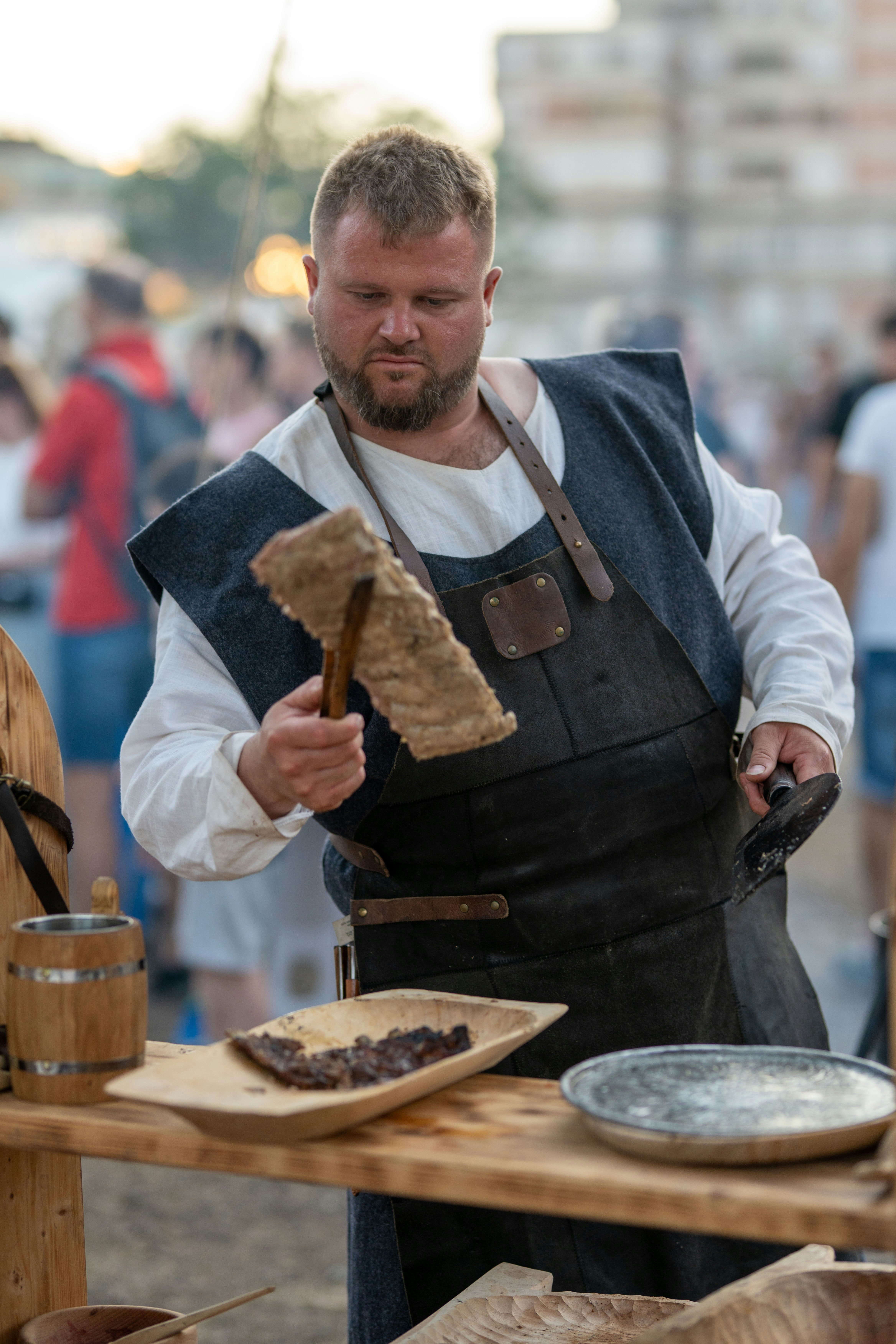 A man in historical clothing prepares food outdoors.