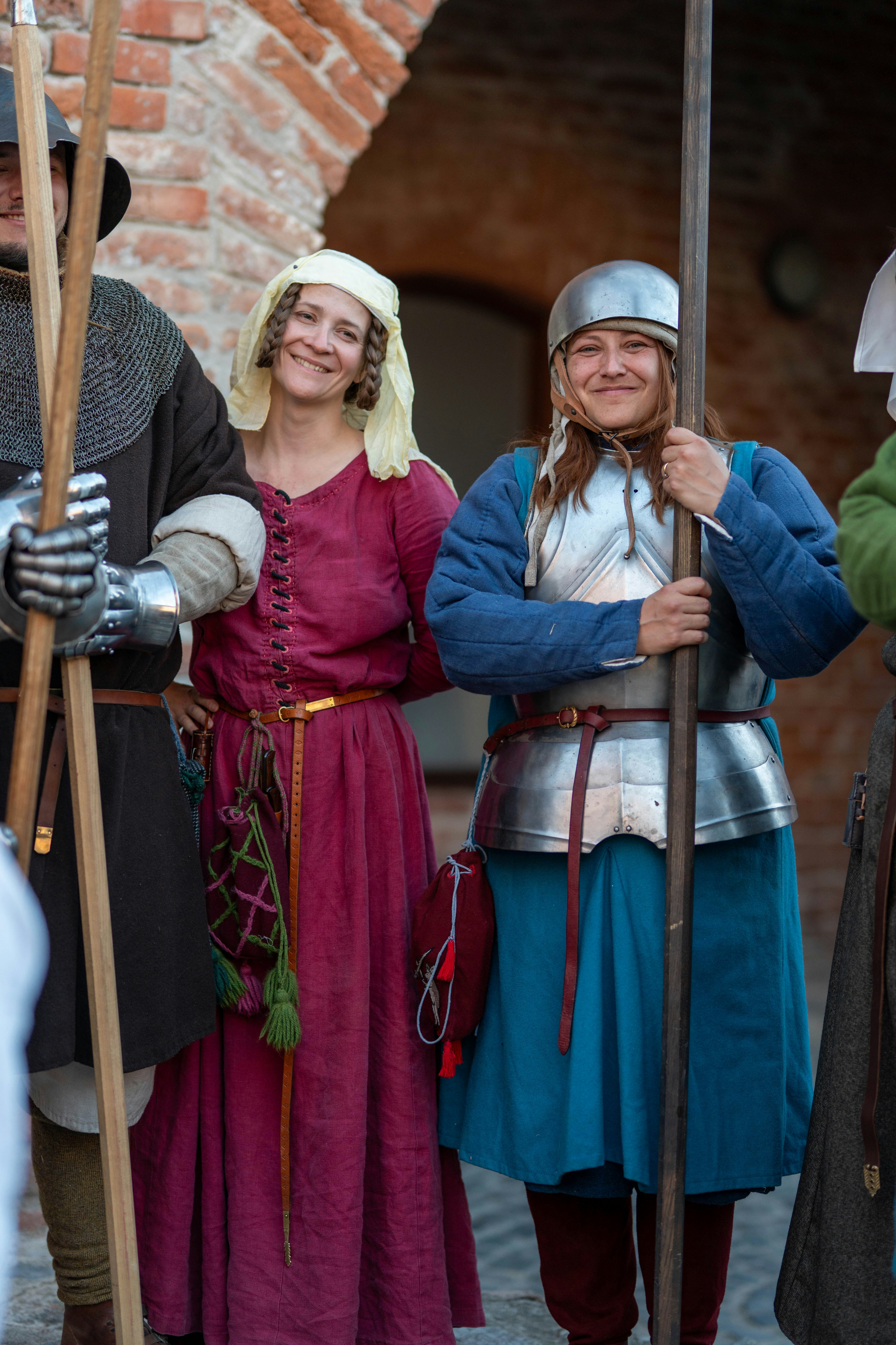 Two women in medieval costumes smiling and holding staffs.
