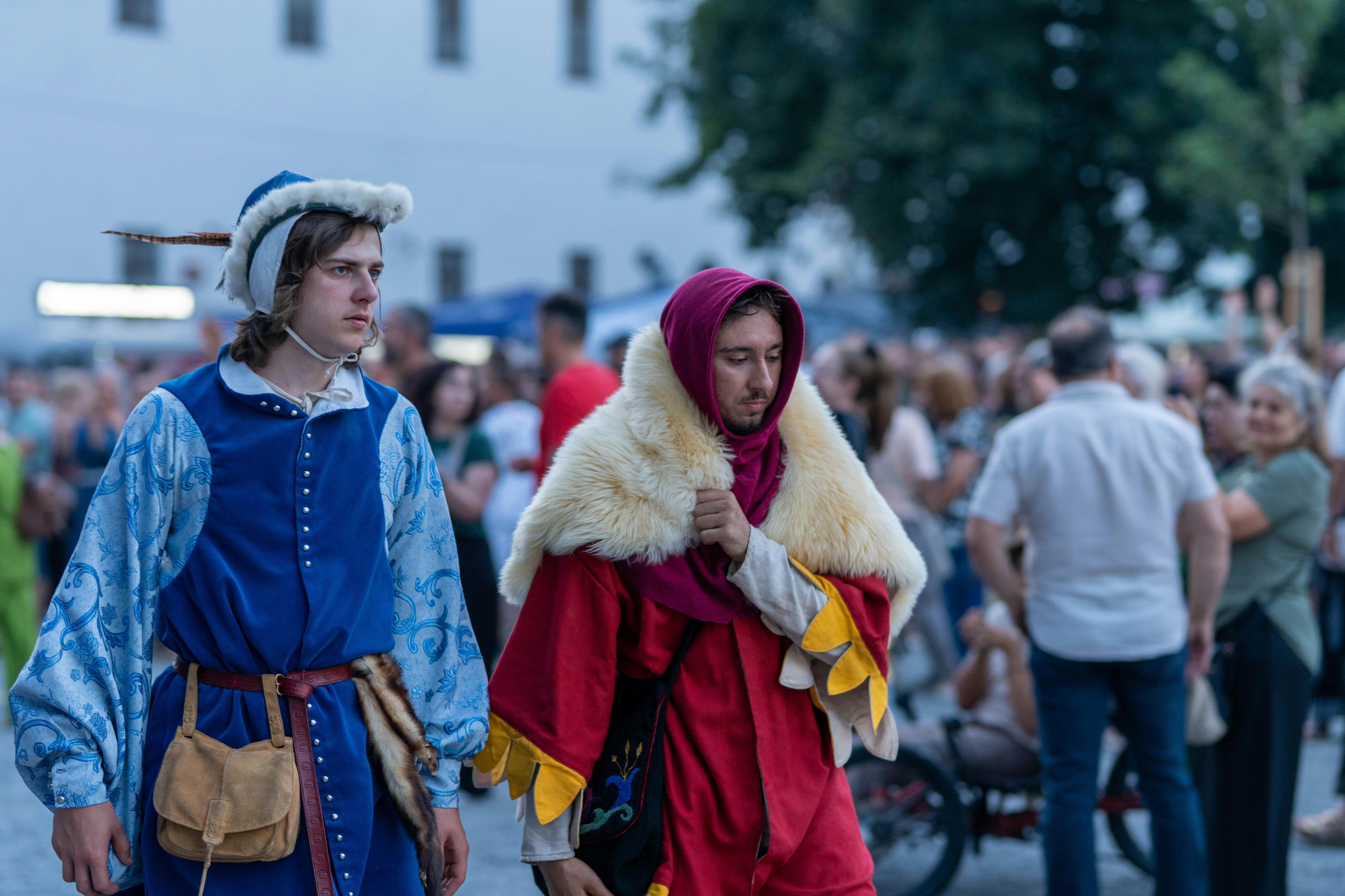 Medieval reenactors in colorful costumes walking outdoors.