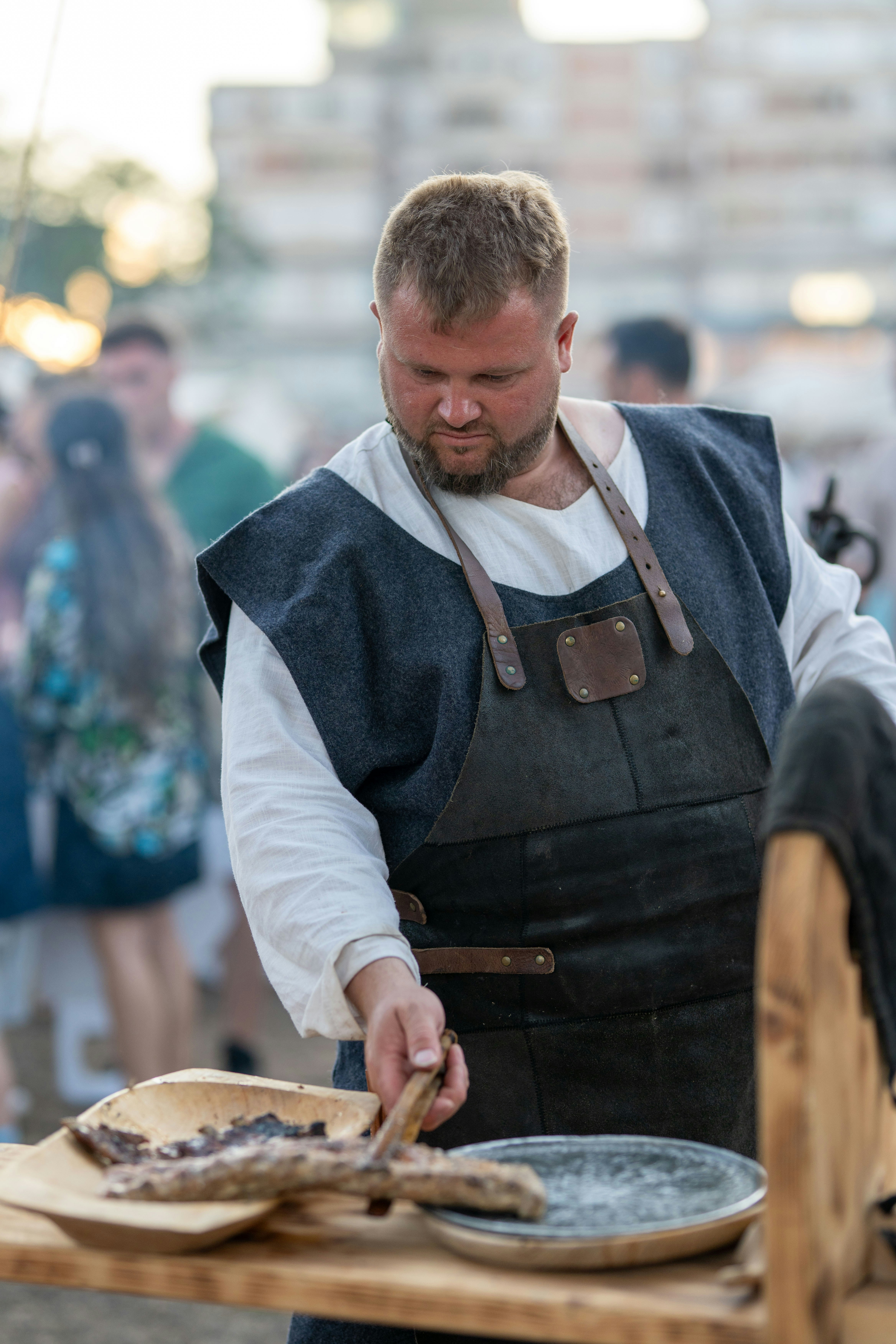Man in historical attire cooking food outdoors.
