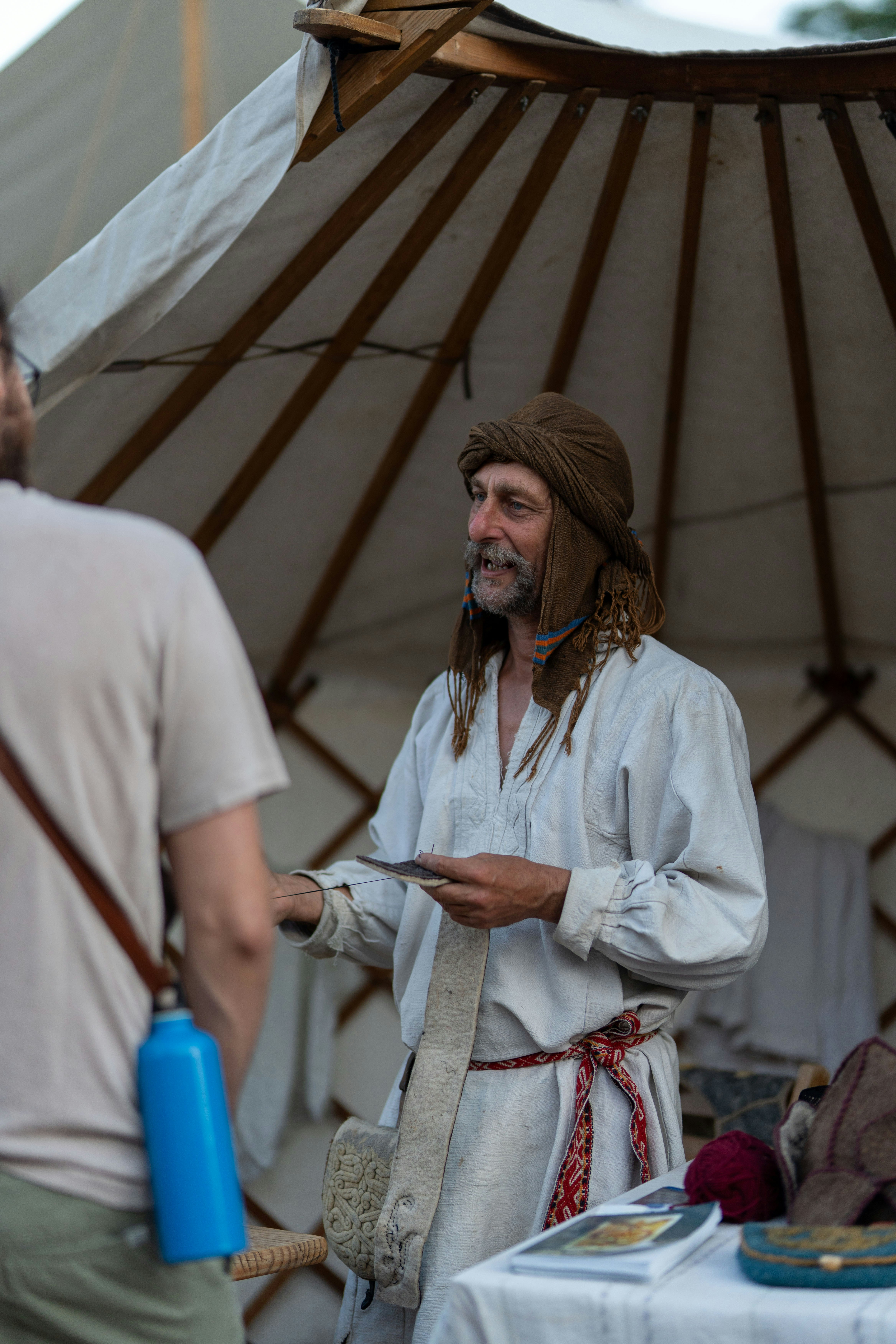 Smiling man in traditional attire interacts with another person.