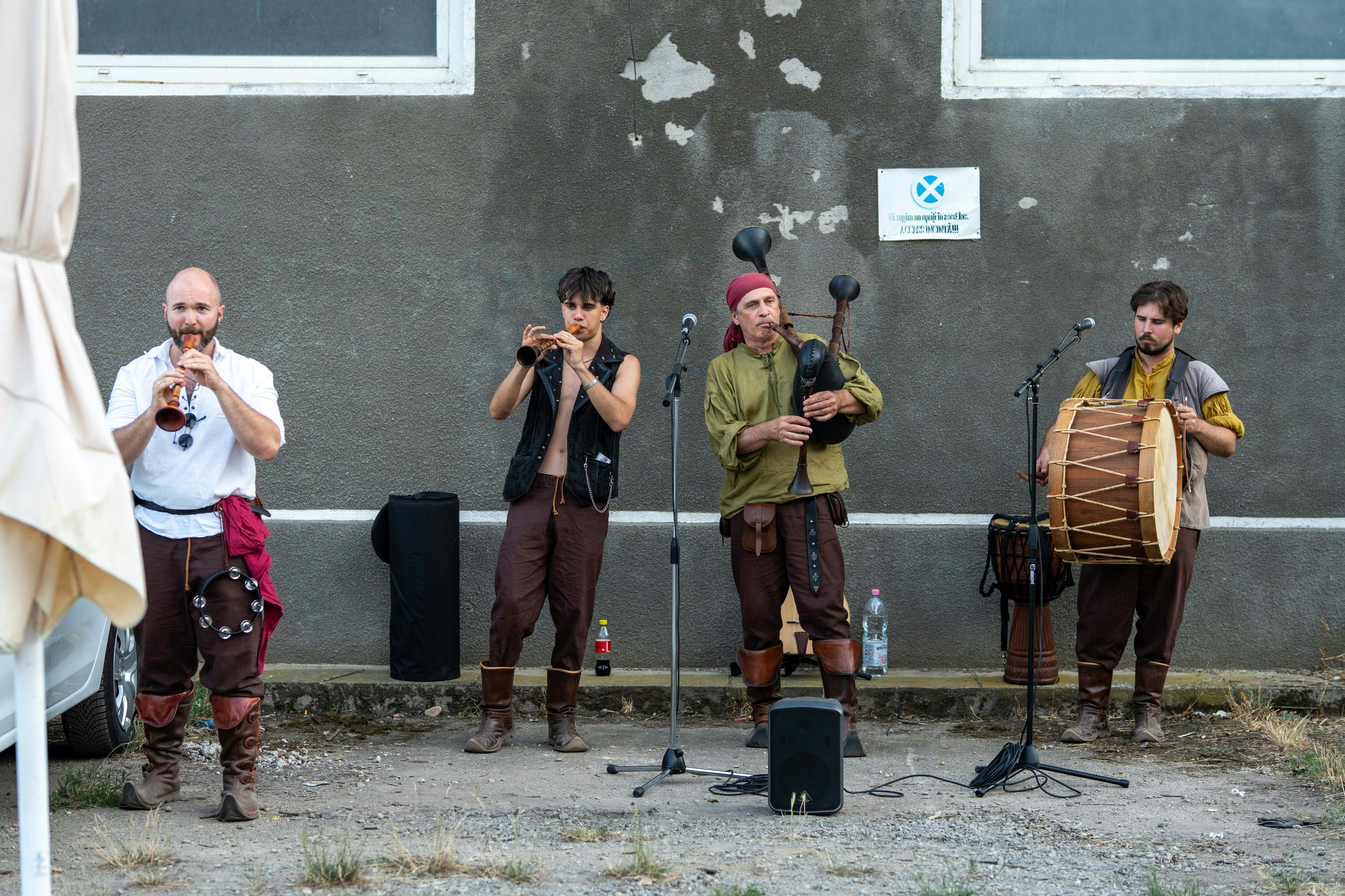 Men in historical clothing play folk instruments outdoors