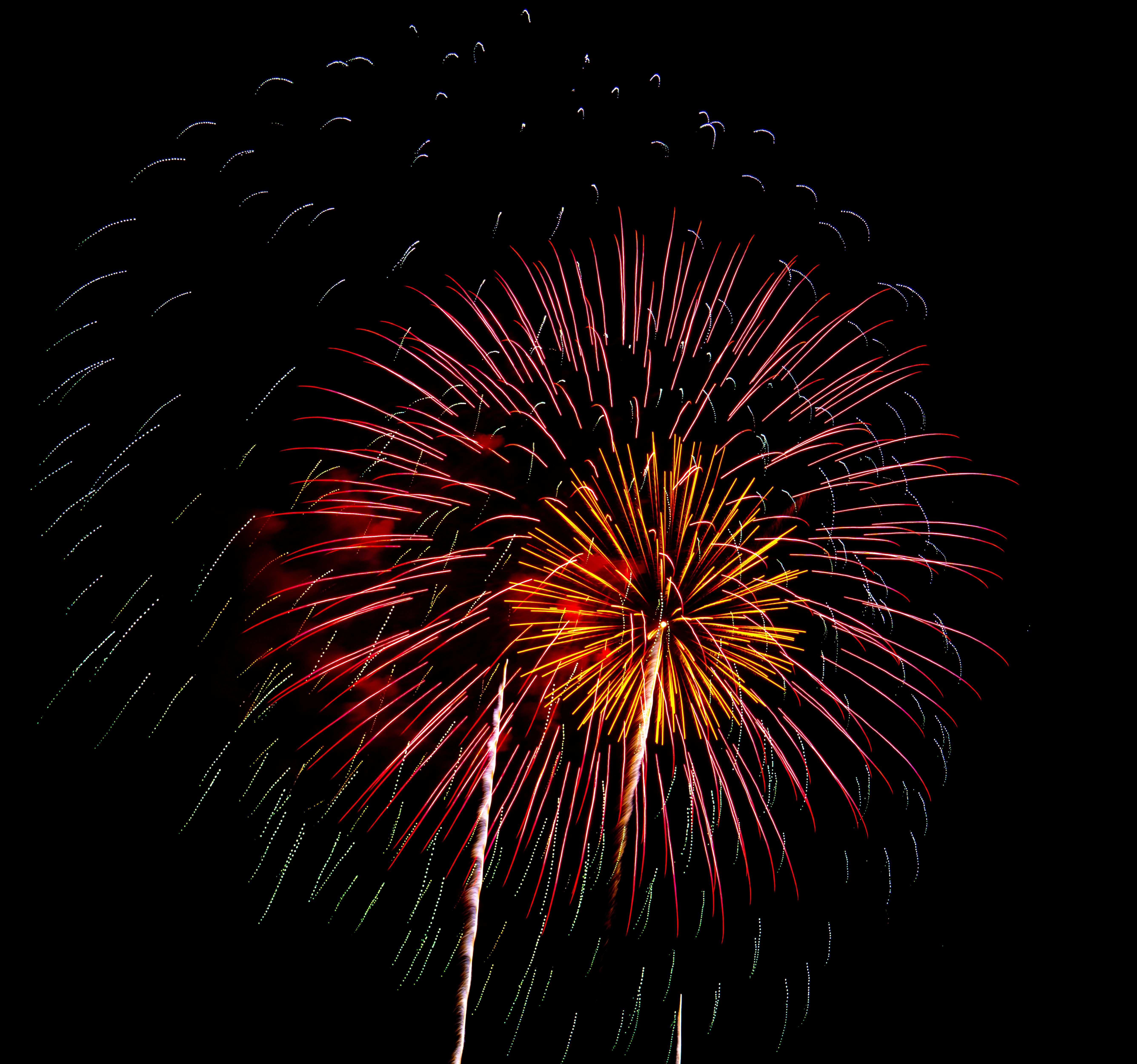 Colorful fireworks explode brightly against the dark night sky.