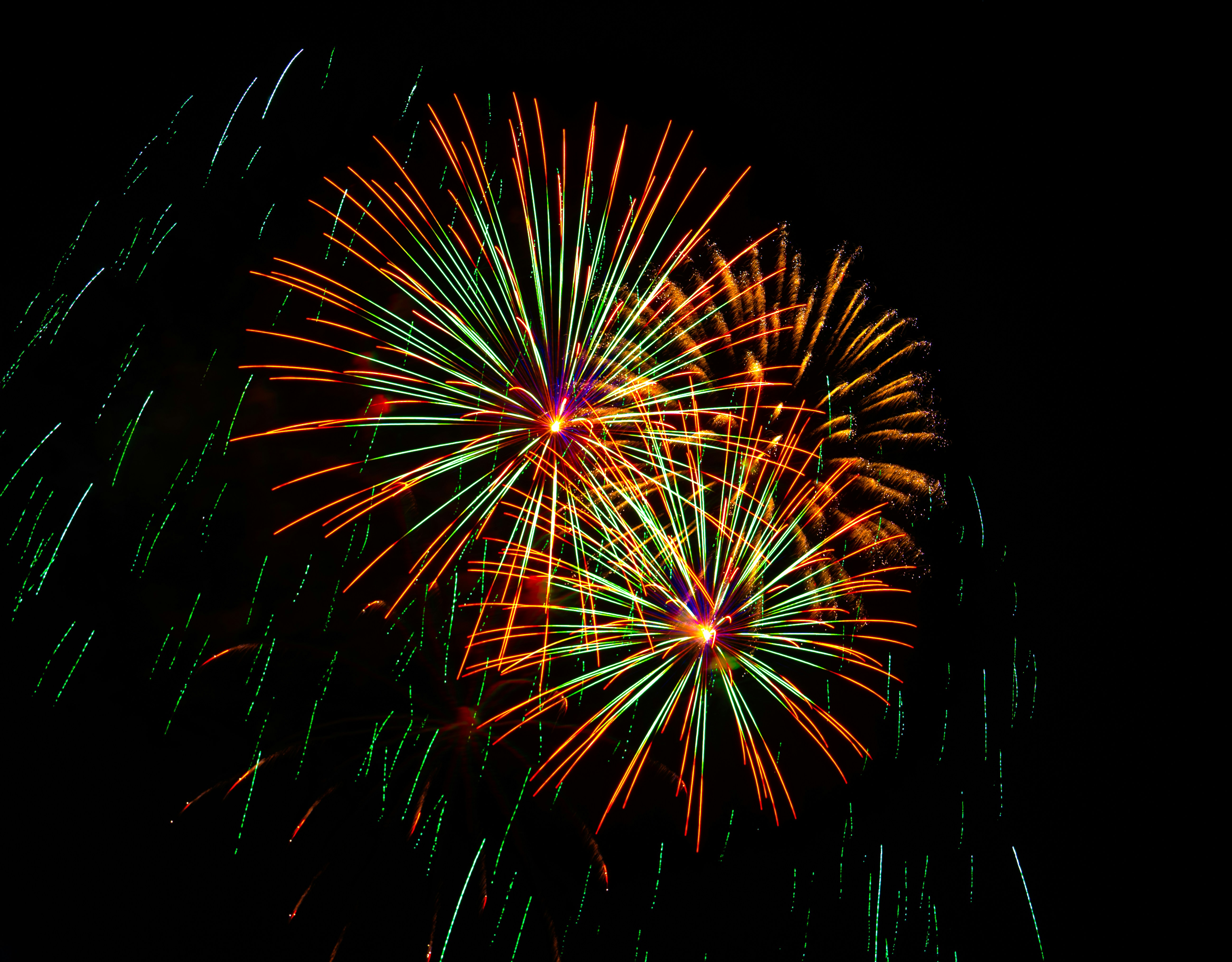 Two vibrant fireworks explode against a dark background.