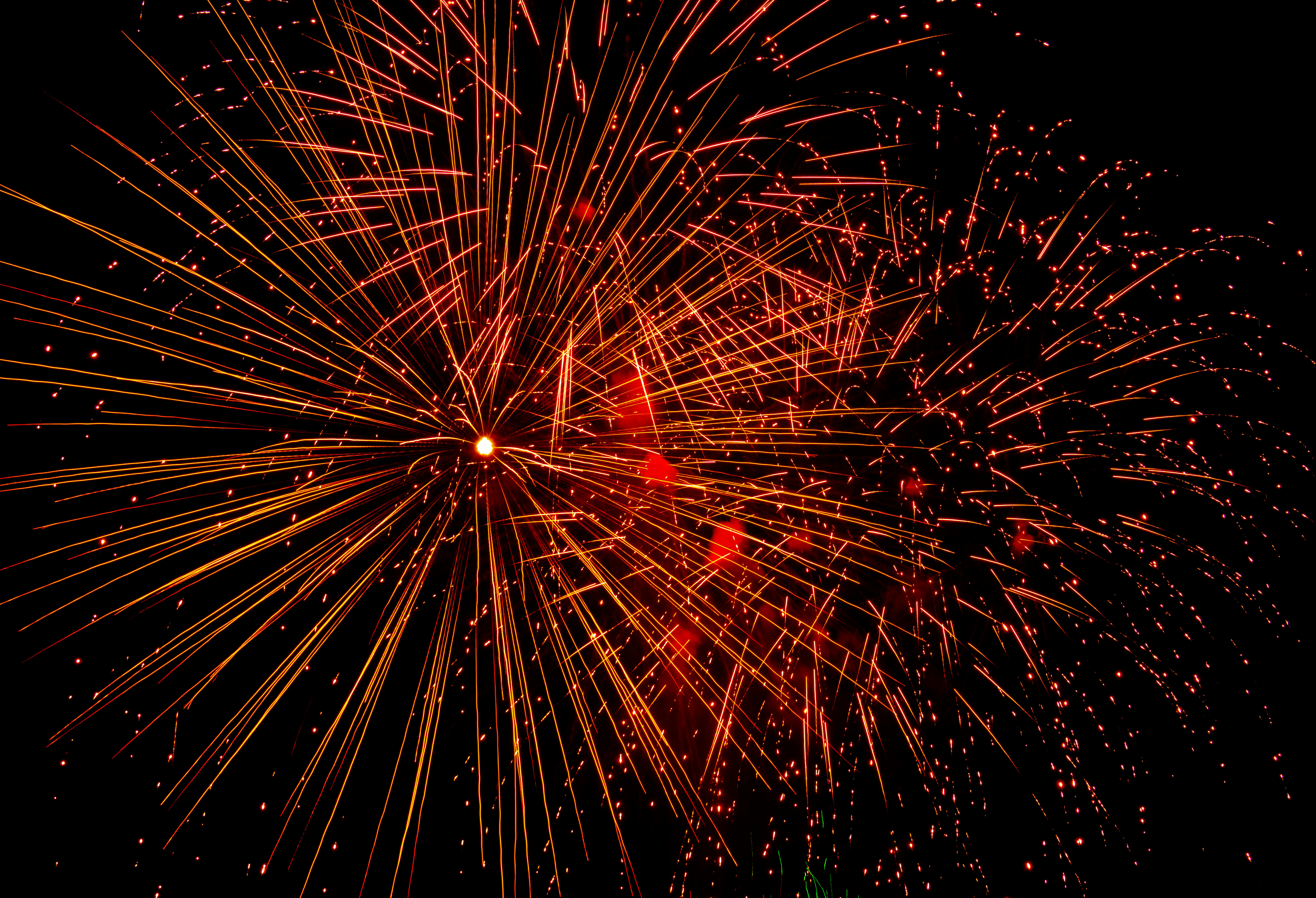 Bright fireworks explode in the dark night sky.