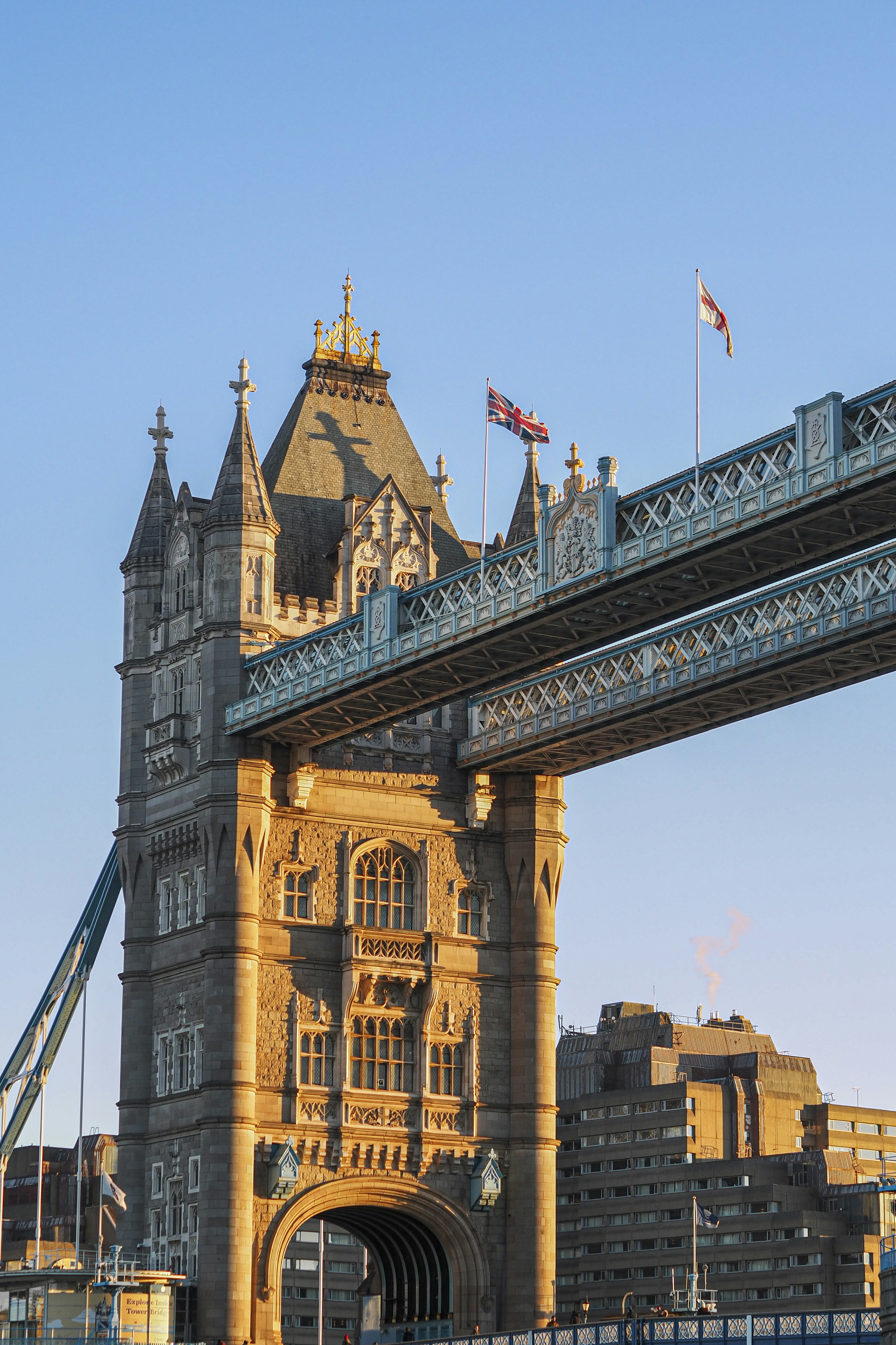 Ponte torre illuminato dal sole con bandiere dell'Union Jack contro il cielo azzurro.