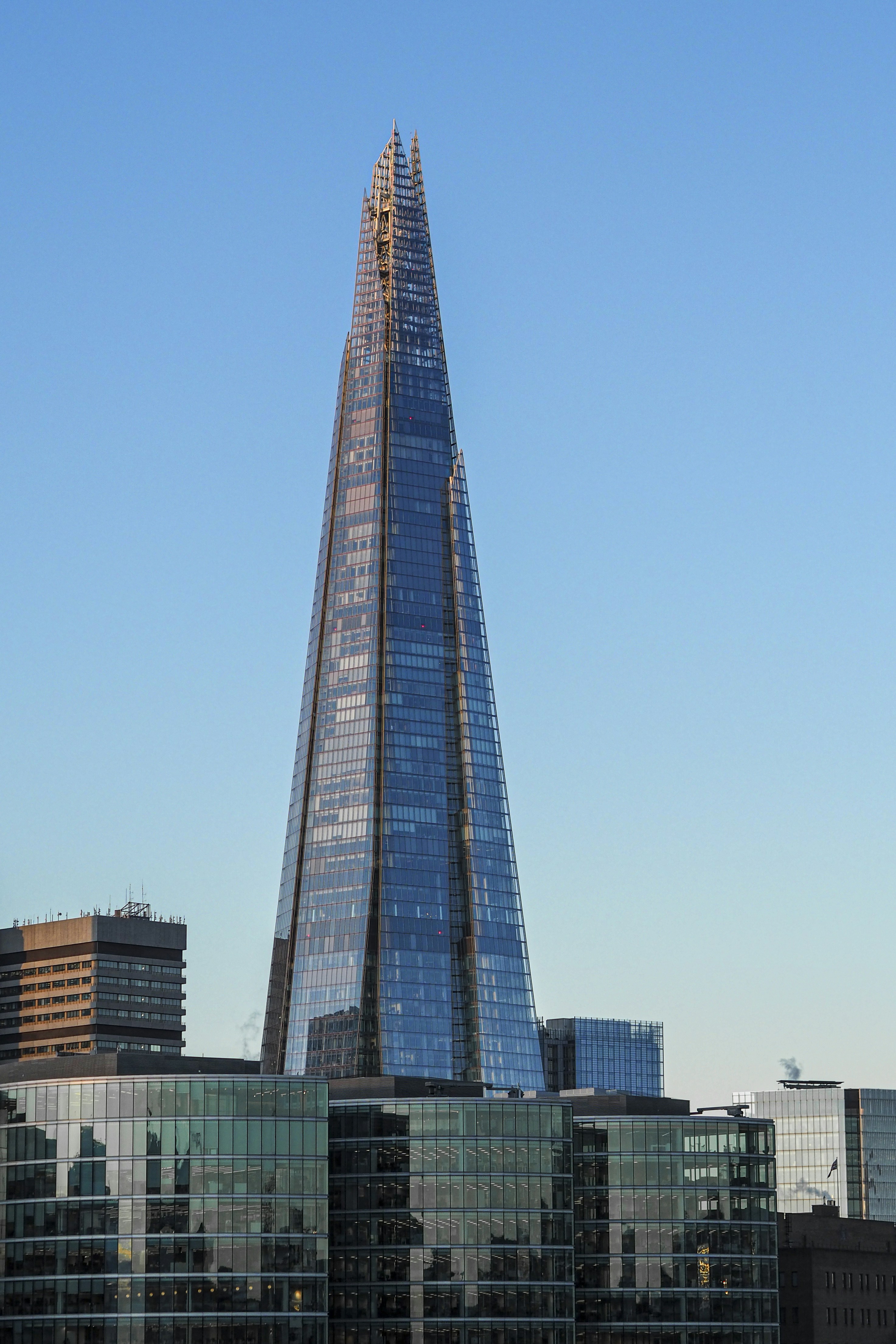 Alto grattacielo di vetro sopra gli edifici cittadini sotto un cielo azzurro limpido.