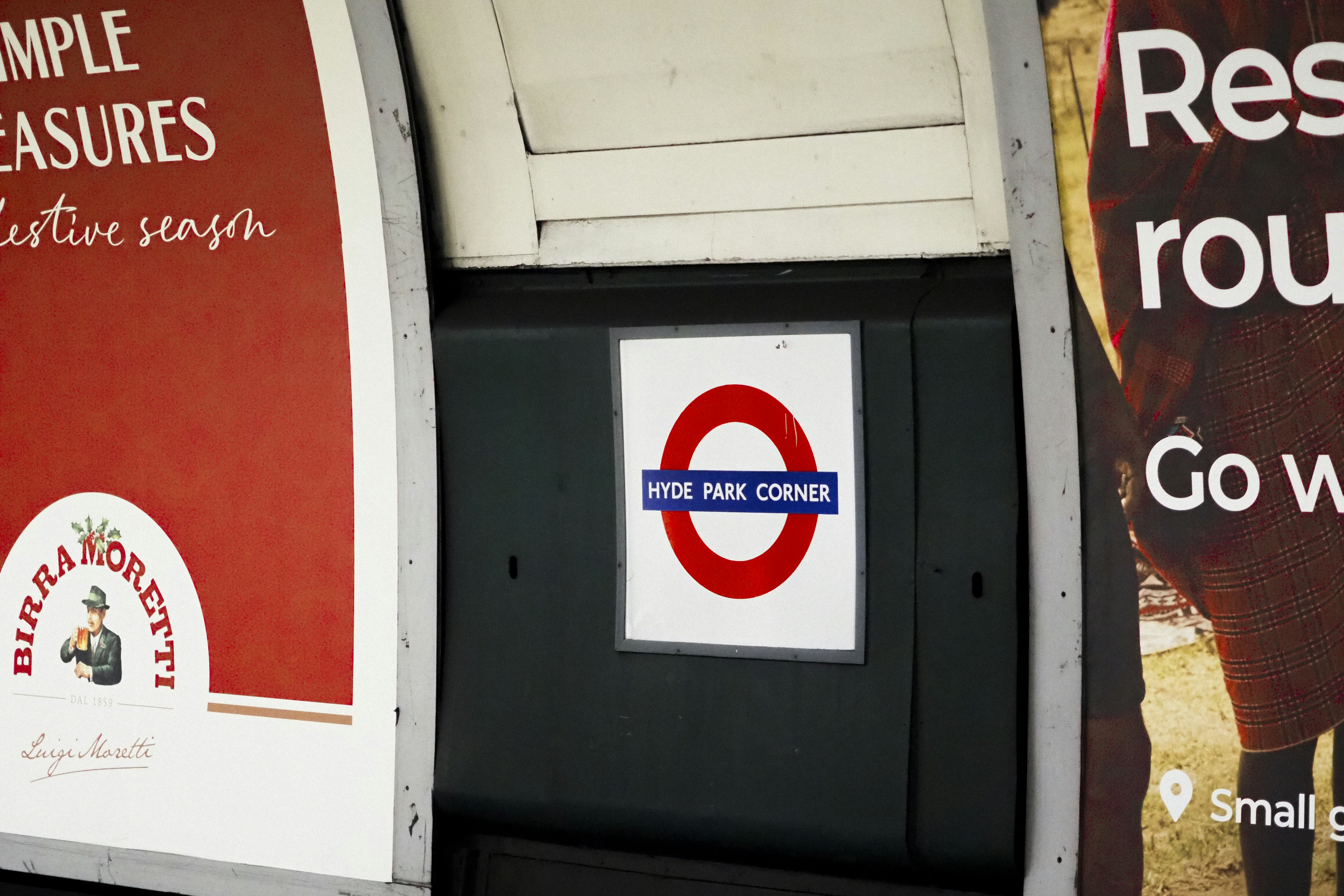 Cartello 'Hyde Park Corner' della metropolitana di Londra tra una pubblicità e l'altra.
